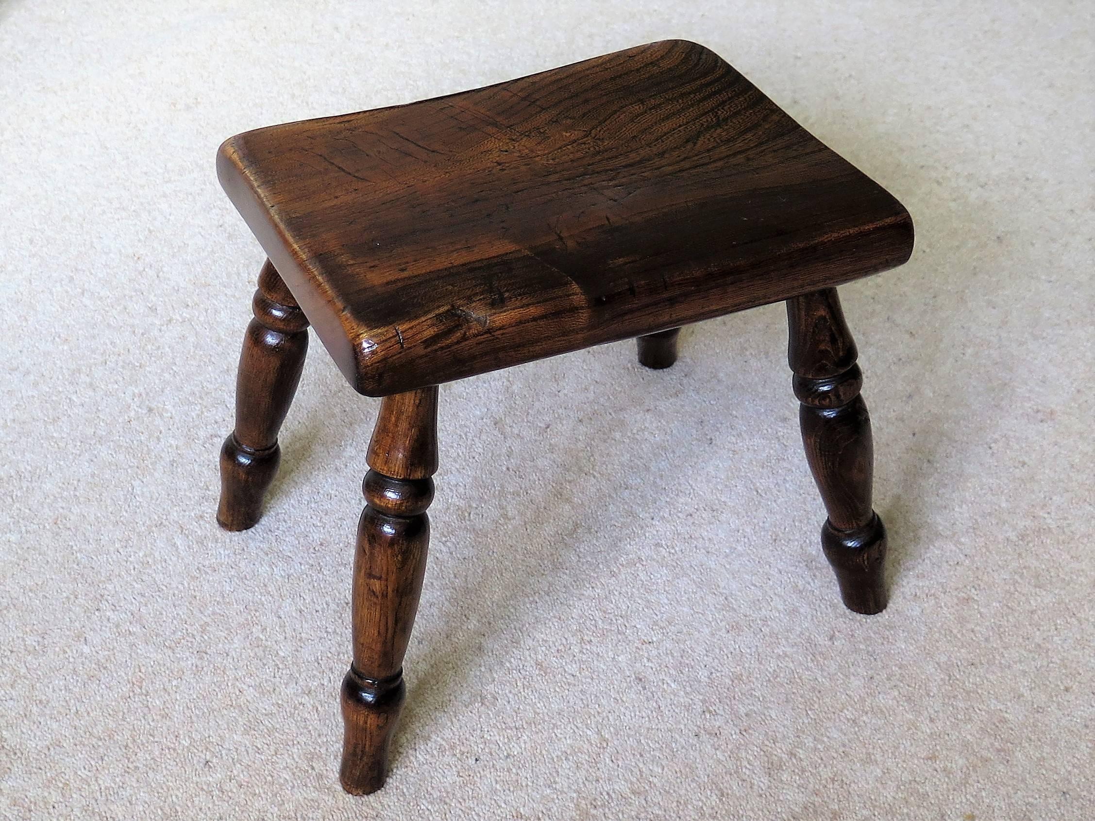 This is a lovely Country Stool made in Victorian England during the 19th Century, Circa 1870.

The stool is made of Elm with a thick solid rectangular top which sits on four ring turned legs. 

The stool has developed a glorious rich colour through