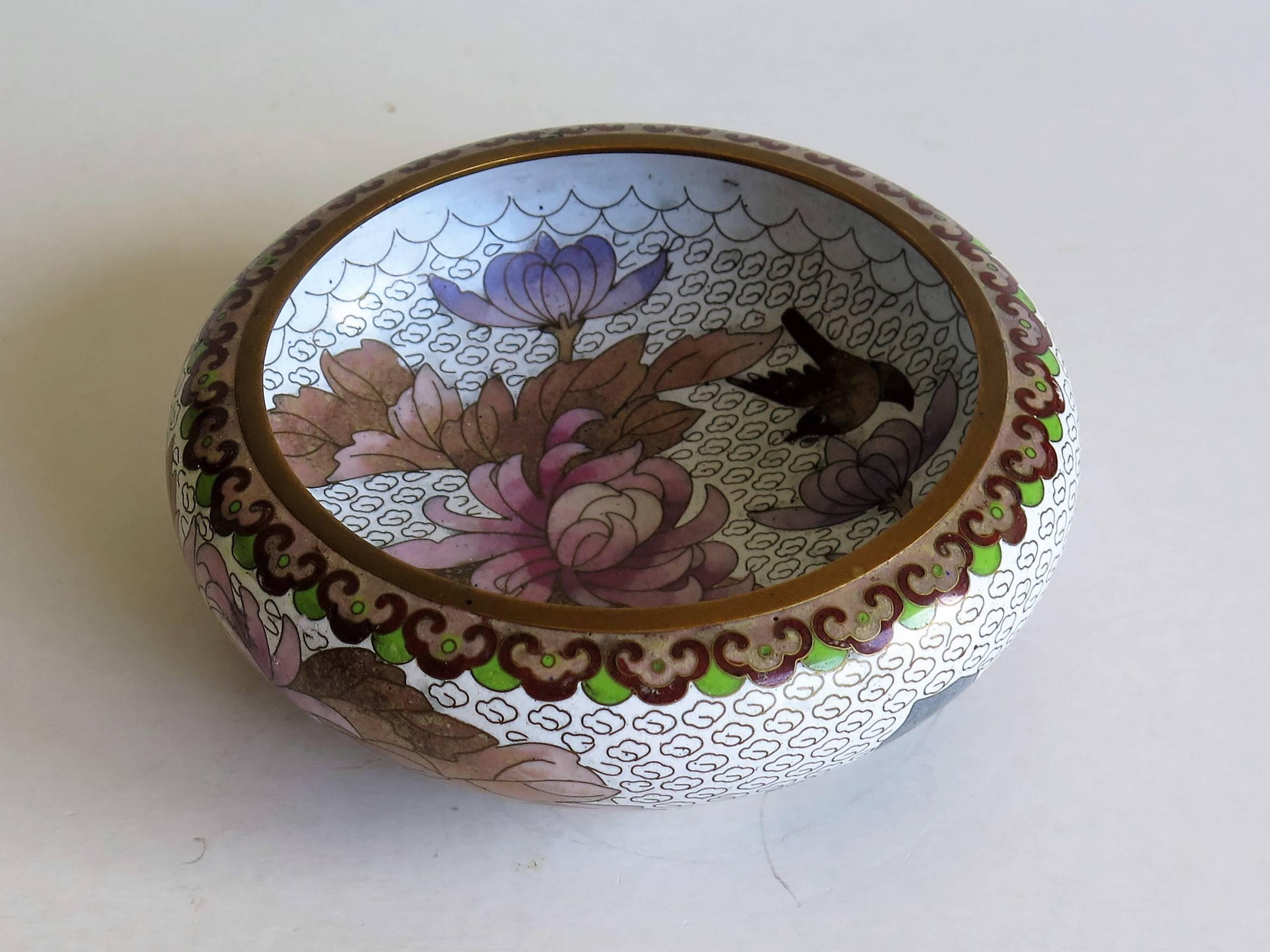 This is a very attractive Chinese cloisonné bowl, of a circular form on a short foot, which we date to the early 20th century, circa 1920.

The decoration shows large peonies and leaves with a bird flying above the flowers, both to the inside design
