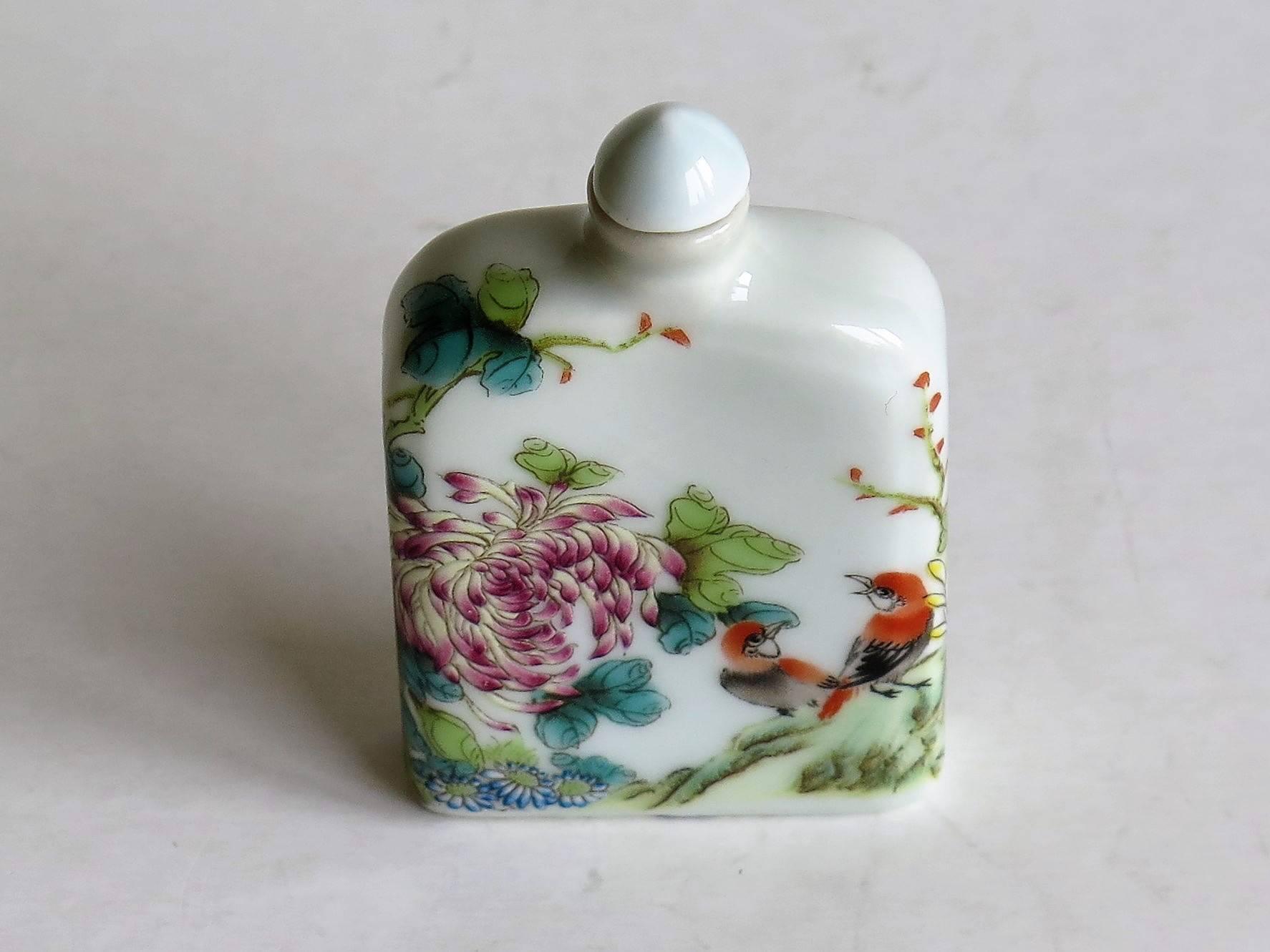 This is a very decorative, hand-painted, Chinese snuff bottle, made from porcelain, circa 1940s. 

The rectangular bottle has a narrow neck with a cone shaped stopper.

The main decoration is hand painted, depicting two colorful birds among