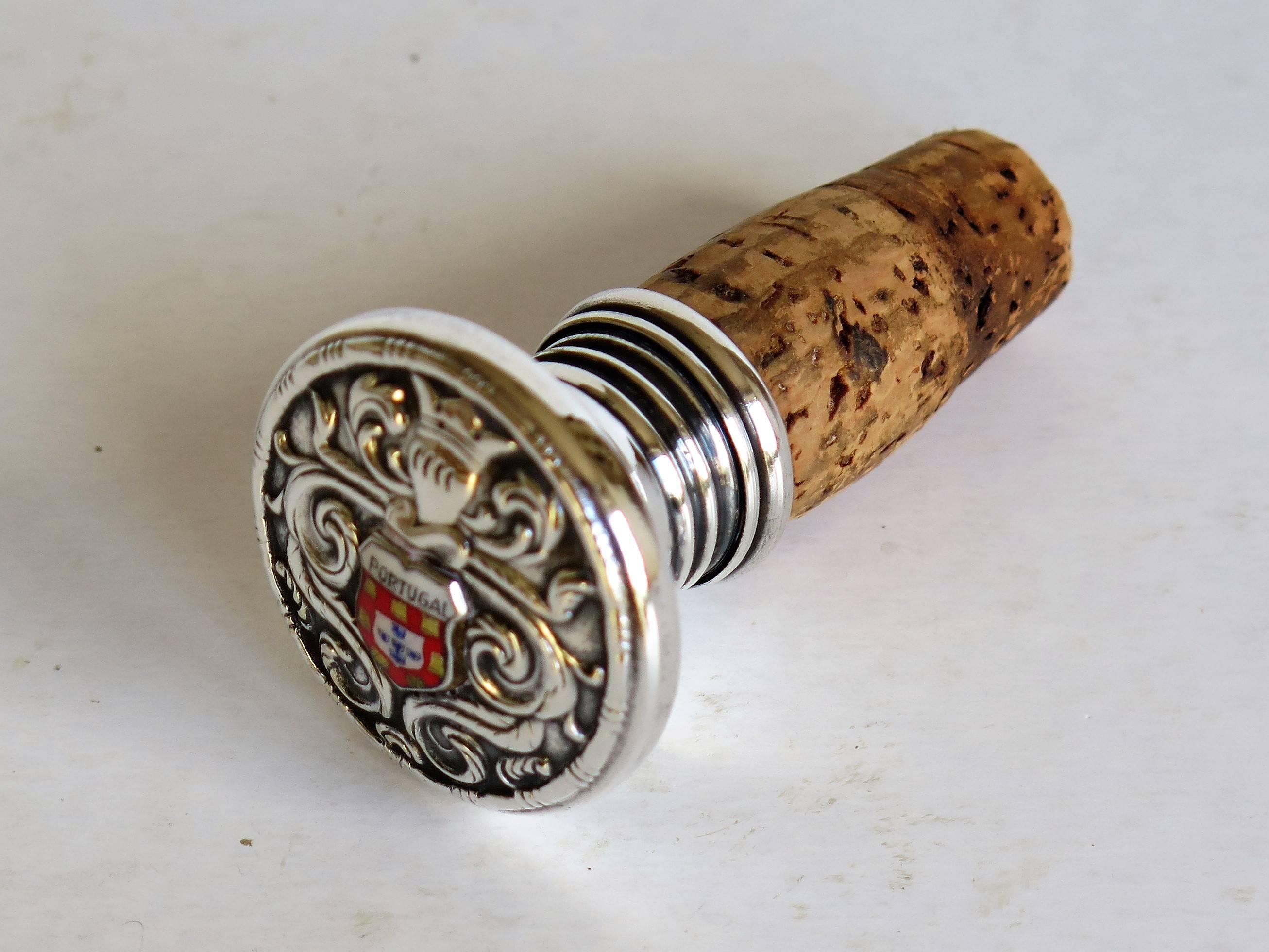 This is a wine bottle or bottle stopper with a circular silver top carrying the Portugal Coat of Arms, 19th century.

The national heraldry of Portugal evolved from royal heraldry, with the royal coat of arms gradually coming to be considered a