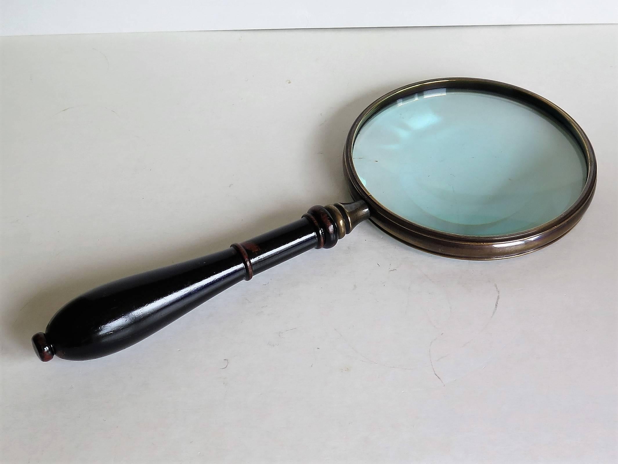 This is a substantial large and quite heavy magnifying glass from the mid Victorian 19th Century period.

The glass is in good condition and is held in a moulded bronze or brass circular frame with a turned support which locates into a nicely hand