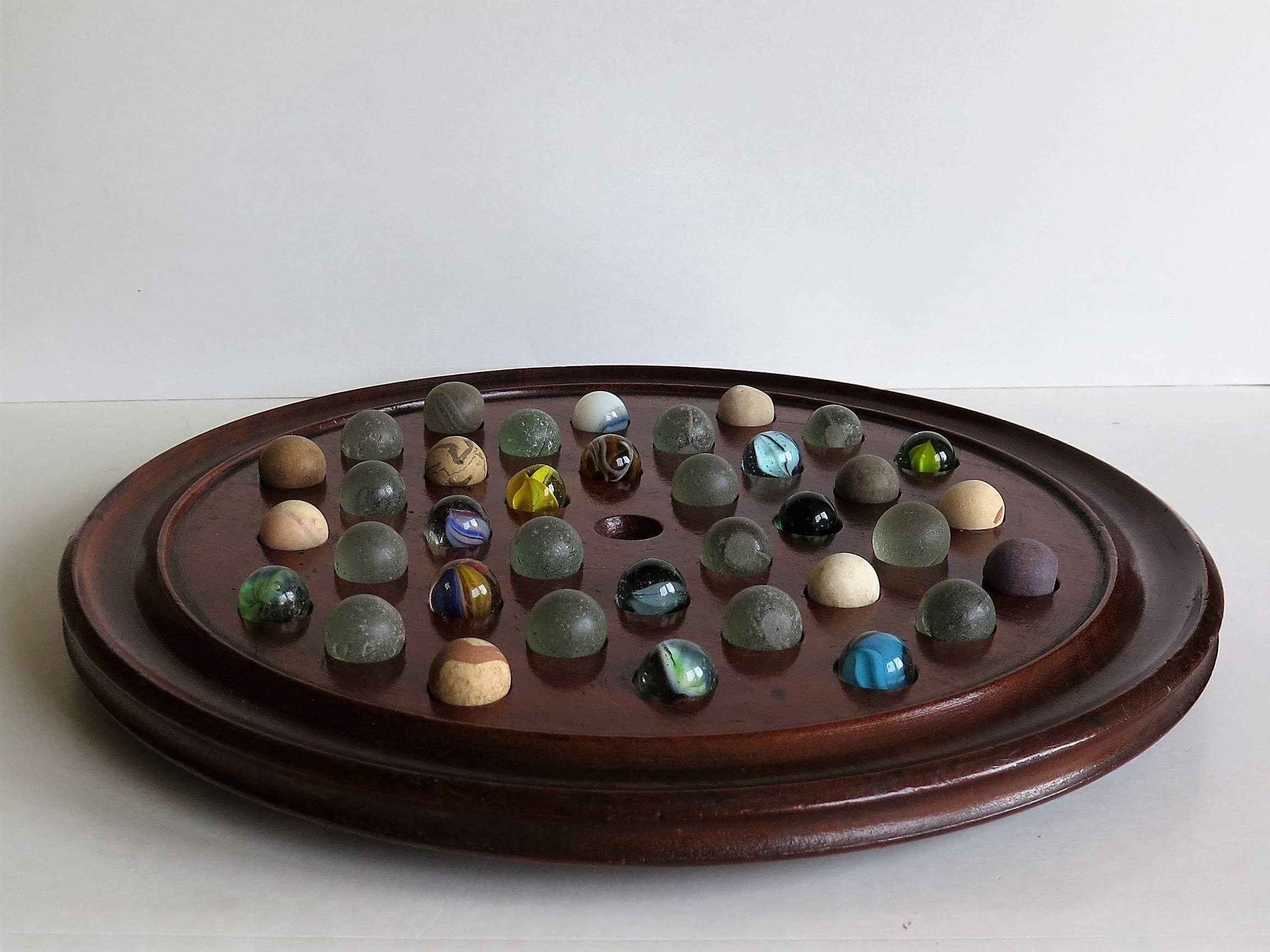 This is a complete game of table marble solitaire from the 19th century of a large diameter, and with 36 marbles.

The circular turned board is made of mahogany and has a much larger 12 inch diameter than is normal (usually they are only 7/8/9