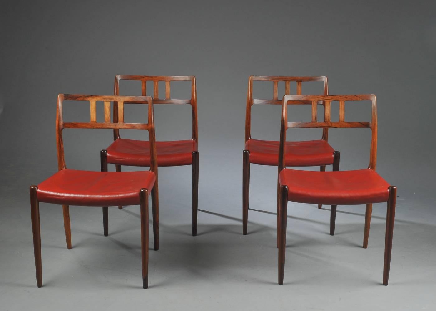 This set of four dining chairs was designed by Niels Otto Moller in 1966 and made by JL Moller before 1970. The chairs retain original red-brown leather seats in excellent condition. The rosewood frames are in excellent condition and display