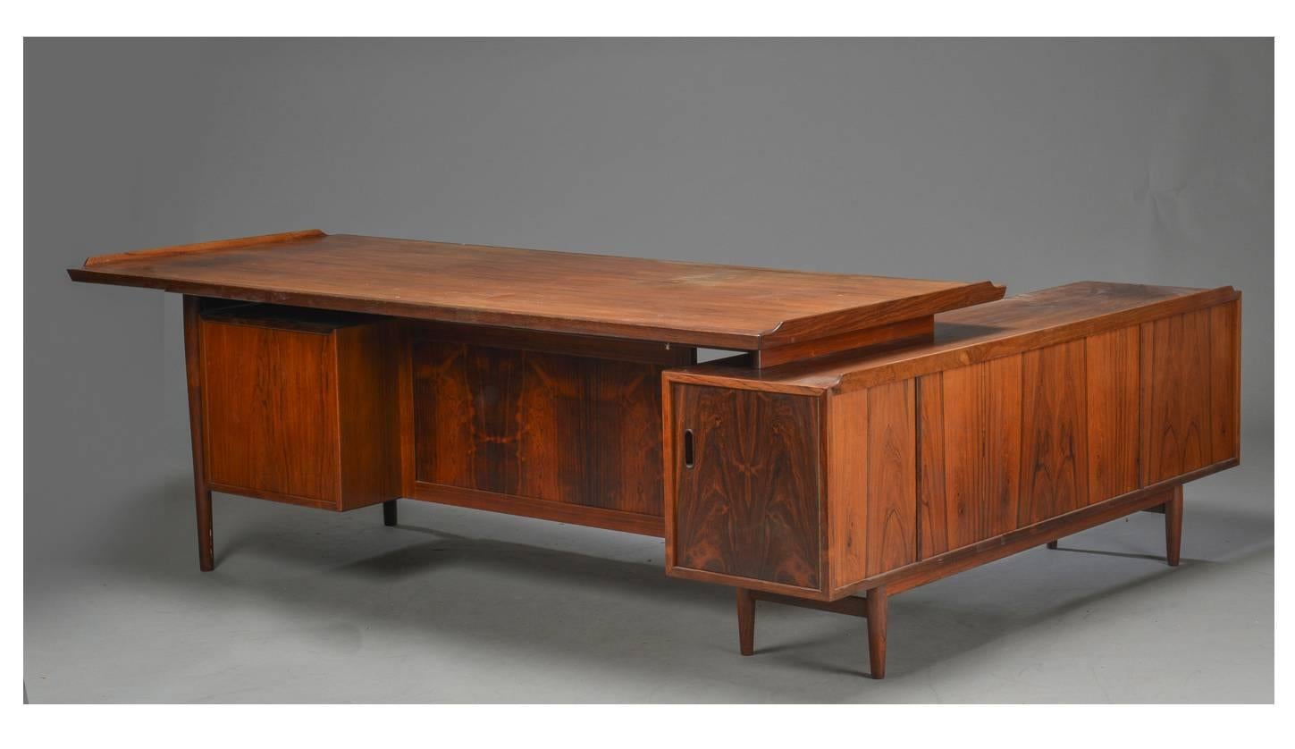 This edition of Arne Vodder's desk with sideboard can be identified as an early example by the black veining in the rosewood and the multicolored pull-out drawers. The desk and sideboard have been repolished. As such, the wear to the polished