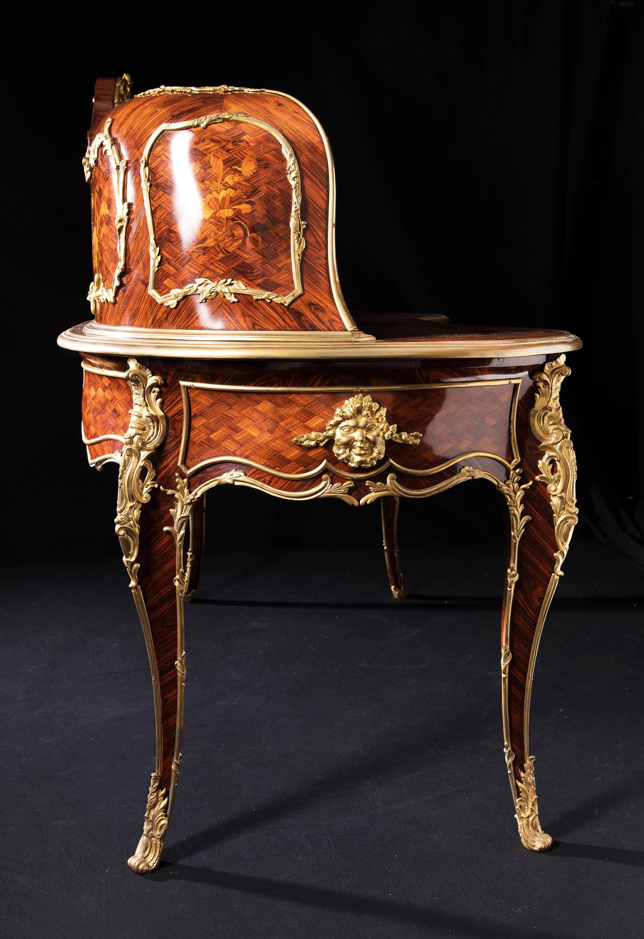 A gilt bronze-mounted kingwood parquetry and fruitwood floral marquetry bureau rognon after Paul Charles Sormani, 
early 20th century.
The upper structure centered by a clock and flanked by two cupboard doors opening to a satine and ebony cube