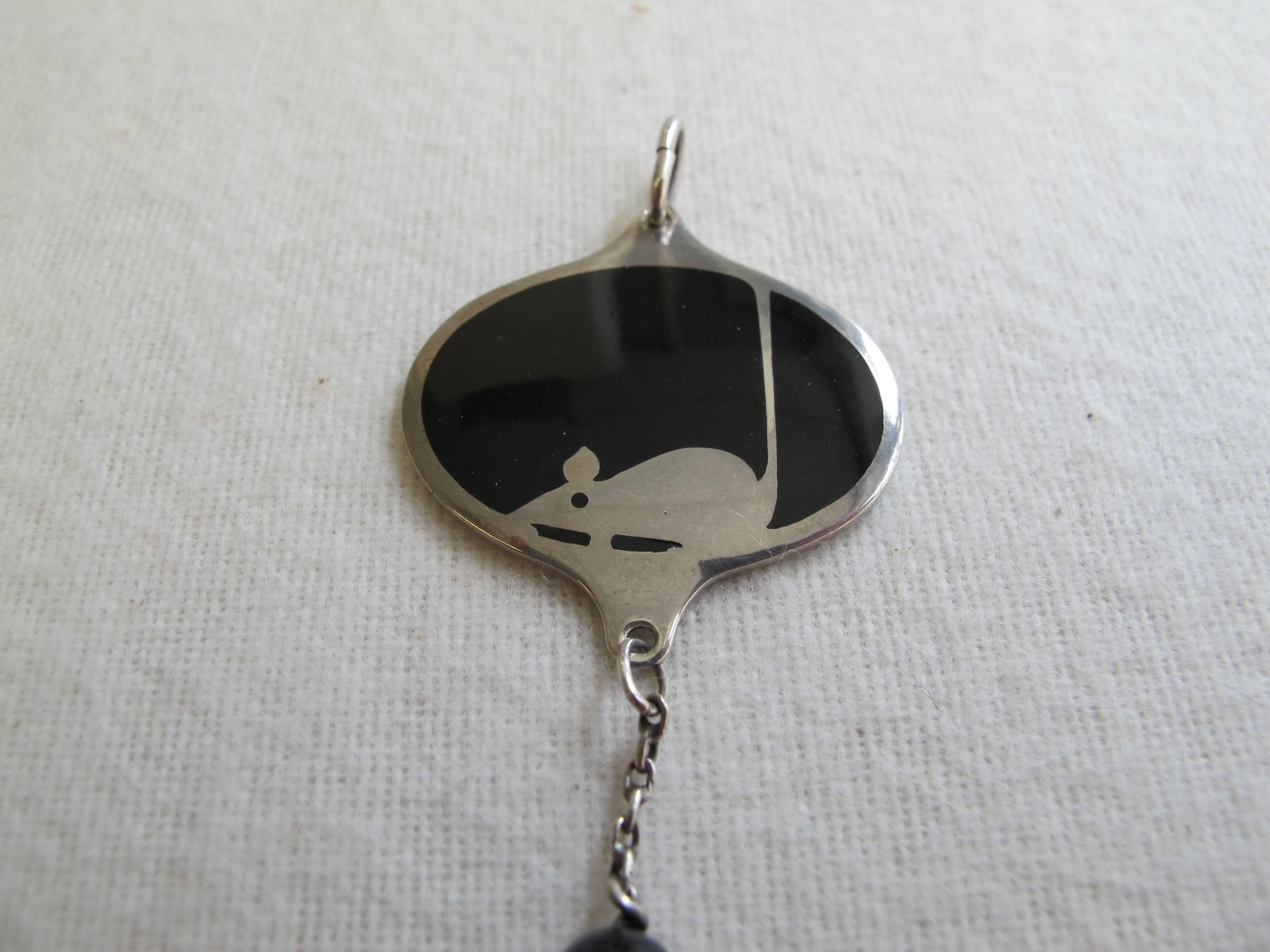 Koloman Moser (1868-1918) designed this silver pendant decorated with a mouse during his time at the Wiener Werkstätte in 1904. The silver mouse is embedded in black enamel in an oval shaped silver pendant and the chain is finished with a black