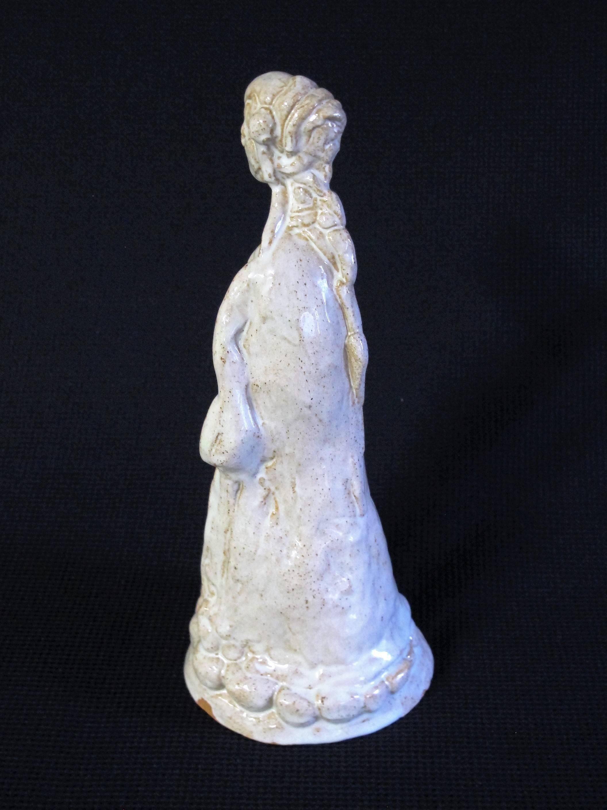 A ceramic sculpture of a woman by Herman Heuff (1875-1945), 1936. The sculpture is glazed in an ivoric white, where the red clay shimmers through.

It is marked on the bottom with black paint: H. HEUFF 1936 M.F.
Carved in the bottom is the mark