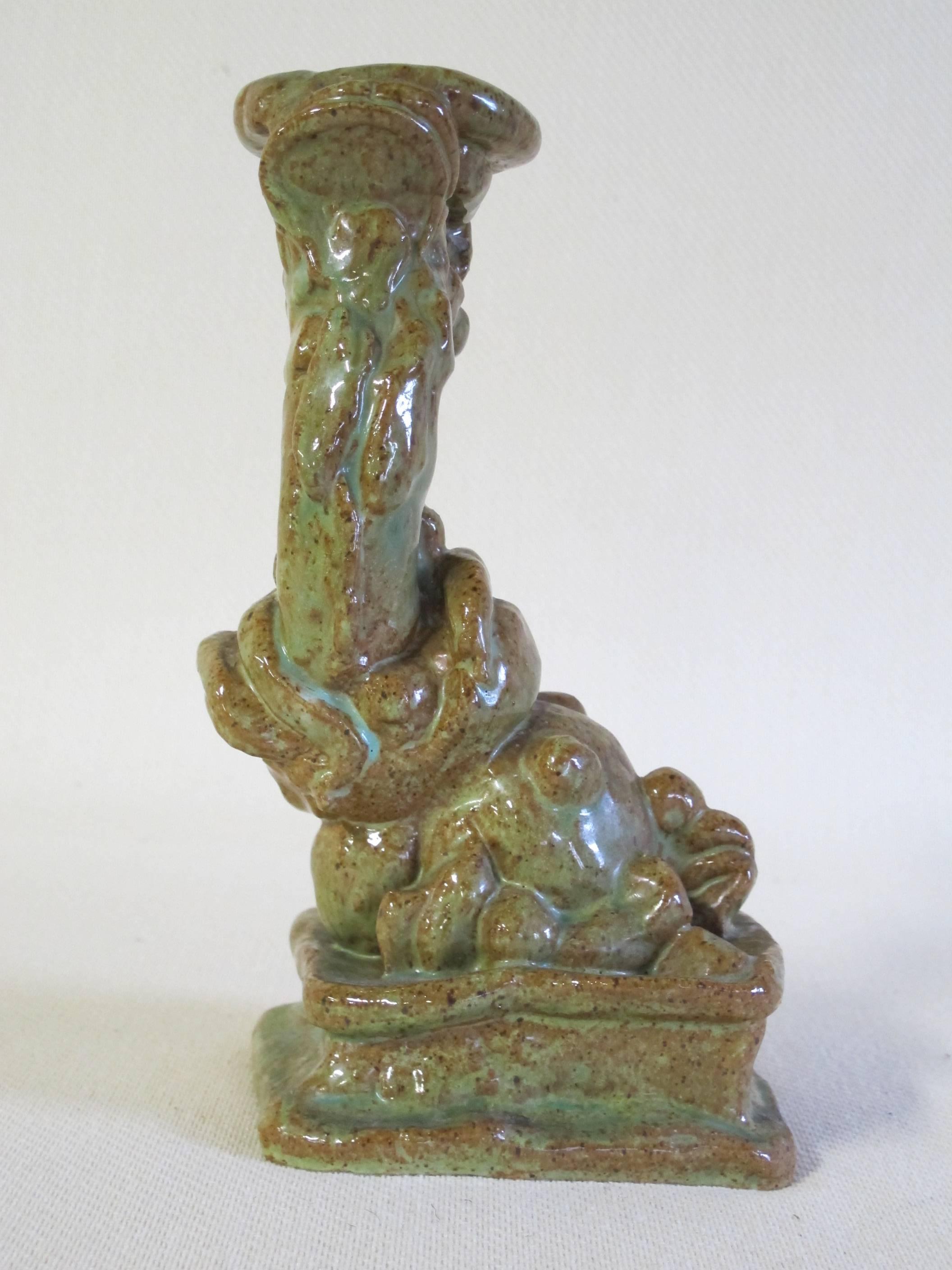 Ceramic candleholder of a mythological creature by Herman Heuff, designed and executed in 1936. The red clay still can be seen through the greenish glaze, which tends to a playful effect.

Carved in the bottom is the mark 'HH' in a circle, for