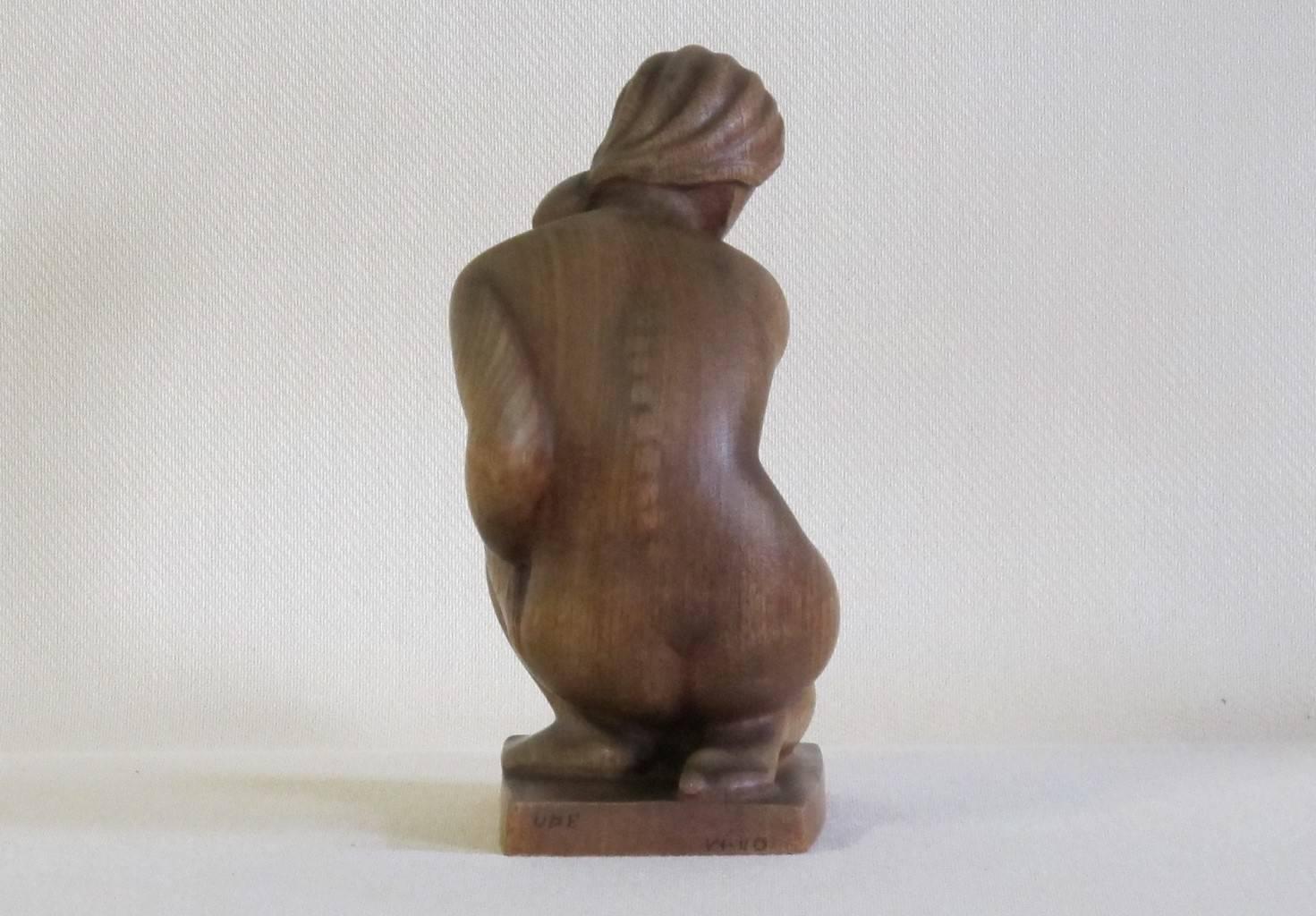 A beautiful sculpture of a nude seated woman made of teakwood, designed by Kurt Harald Isenstein. The woman drapes her hair to the side of her face, whereas the sculpture shows a great mastery of craftsmanship, as the wooden veins follow the forms