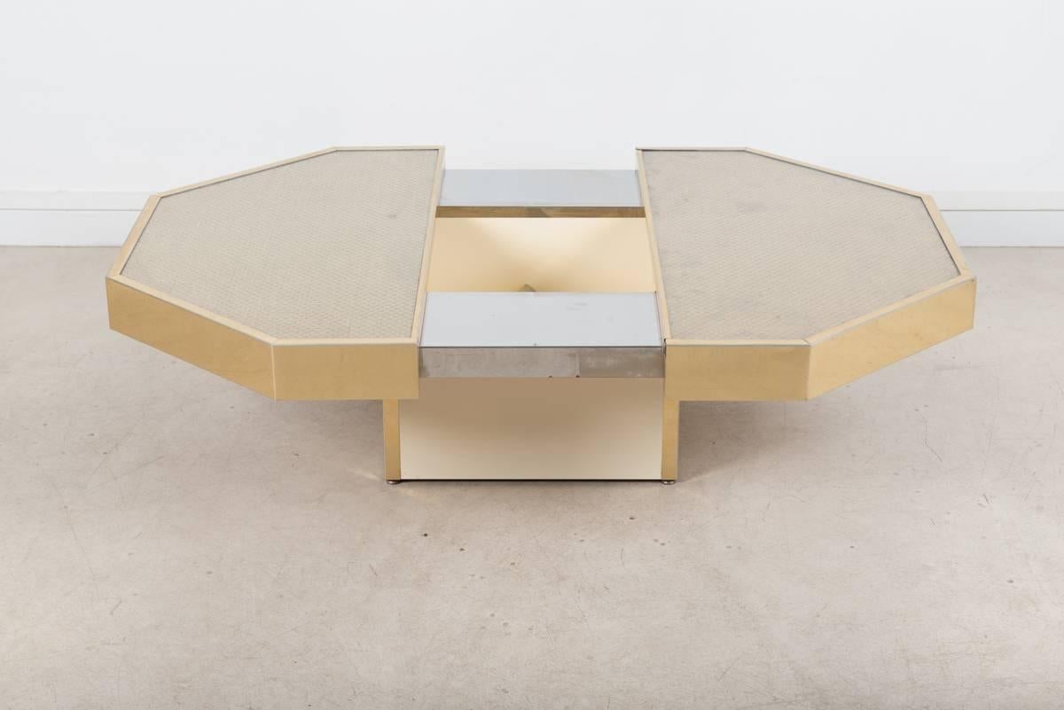 With this octogonal shape, the coffee table designed by Willy Rizzo has a glossy gold fiber coating. The tabletop slides on side to open a compartment of storage nestled in the middle of the table.