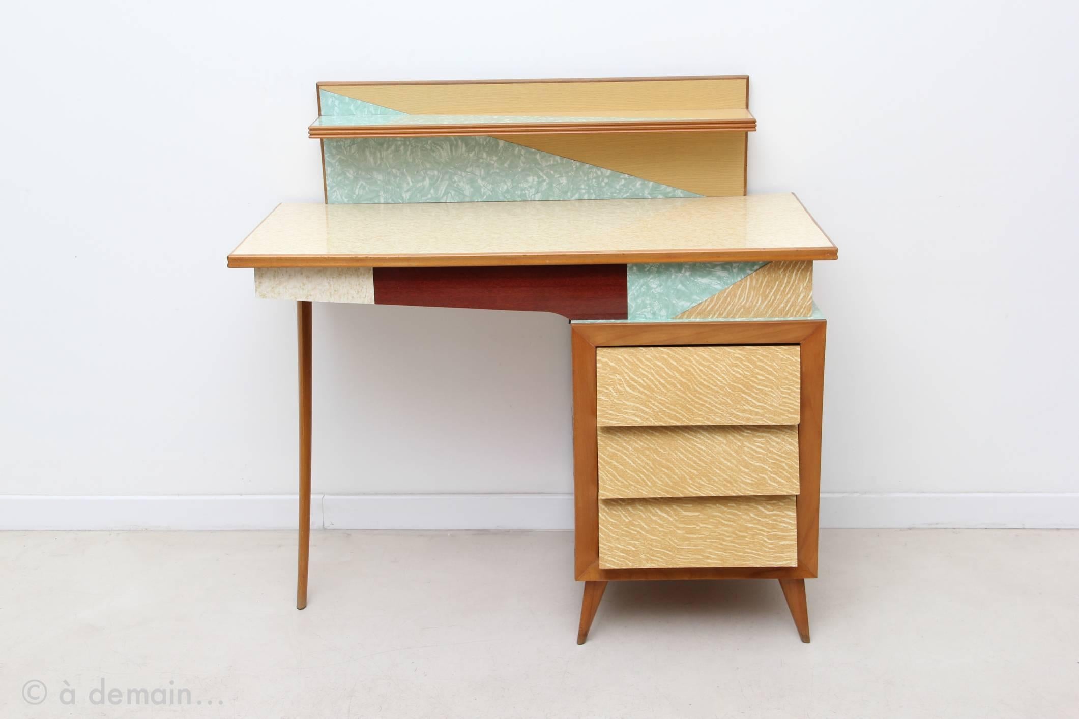 Aamazing desk, surely an Italian design from the 50s in the style of Melchiorre Bega. It has its own style really, very original with its one foot only on one side. Beautiful with its patchwork of melamine, one shelf and pretty line of its 3