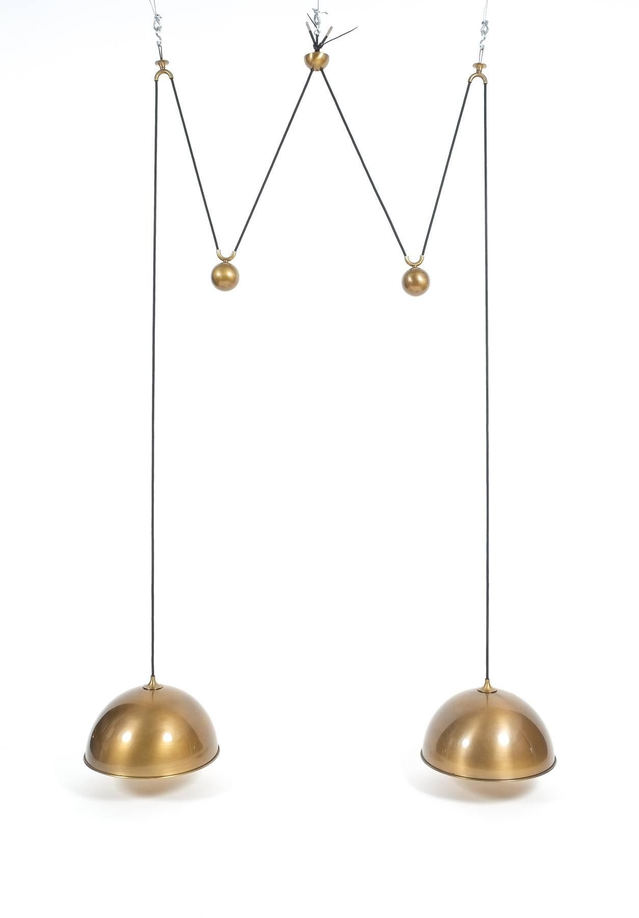 Elegant double counter balance pendants by Florian Schulz with a burnished brass finish and heavy counterweight to easily adjust the light in height. Each light is adjustable in height without affecting the other. Excellent condition, it holds two