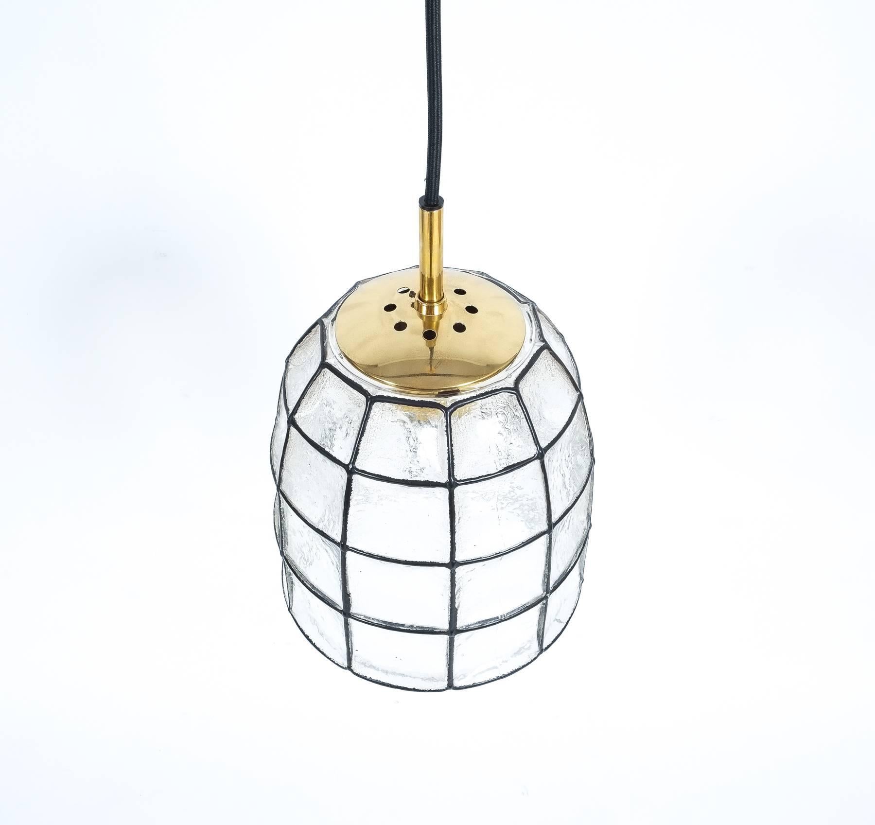 Pair 'iron' and glass bell-shaped pendant light by Limburg, Germany. Priced per piece. The fixtures feature a concaved thick clear glass shade with rectangular black accent 'iron' elements. The hardware is made from polished brass. It holds a single