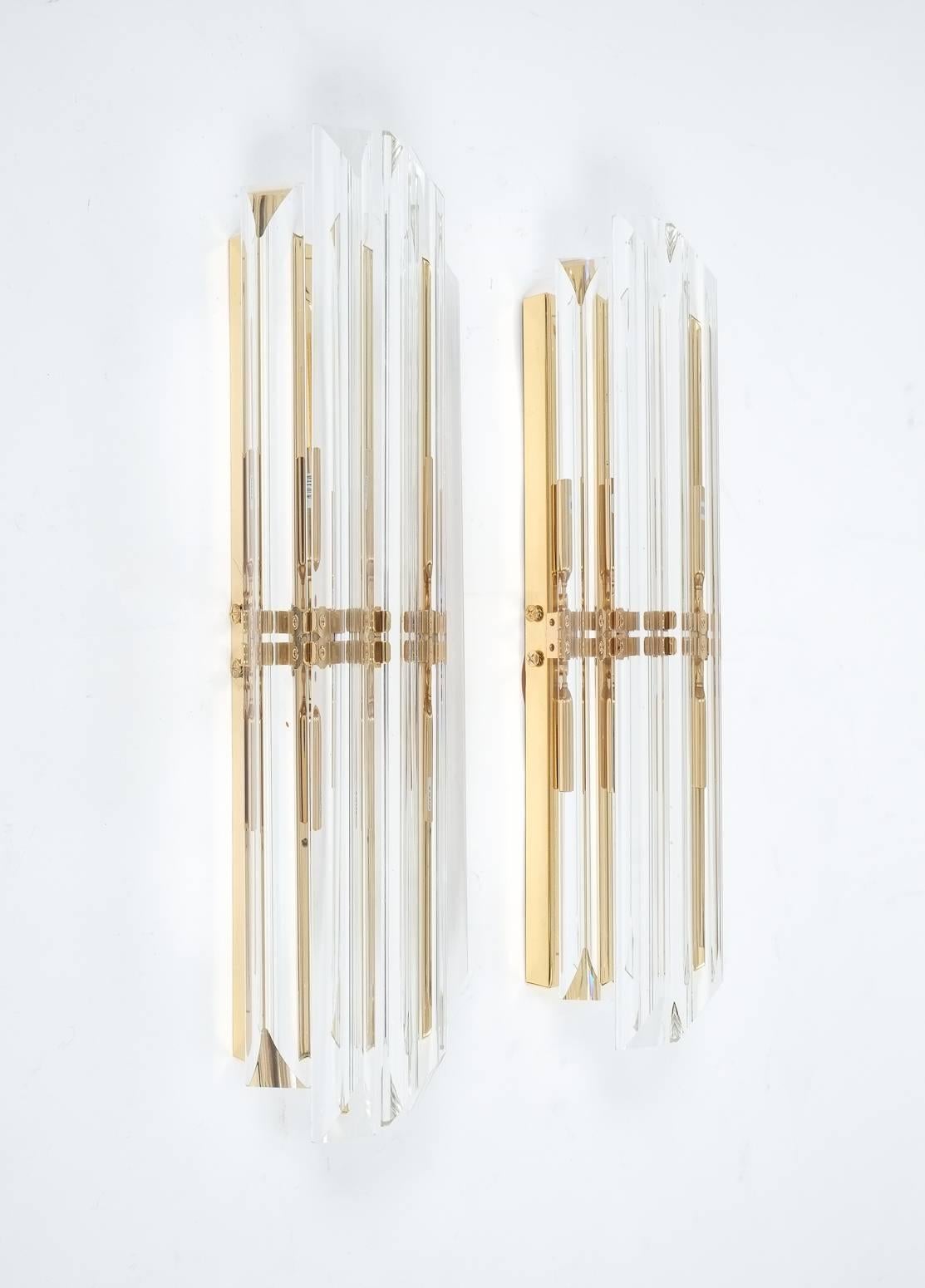 Elegant pair of 17.5" Murano glass wall lights featuring four long crystal clear glass "triete" prisms each attached to a brass structure. Each light holds two bulbs with 40W max (80W in total); the condition is excellent, restored