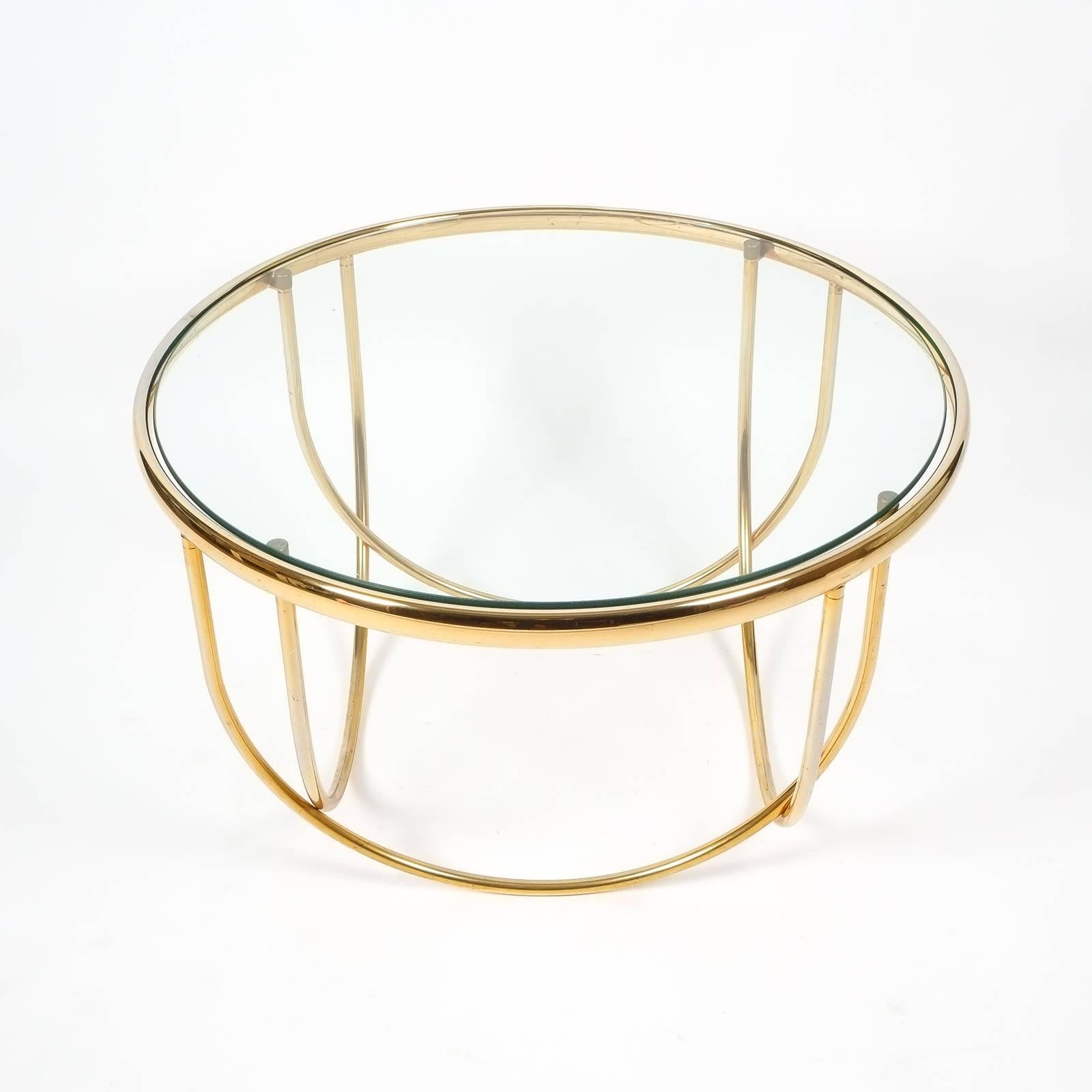 Nice pair of french 31 inch (diameter) brass tables with entwined bended tubes and floating glass top. The brass plating shows some rub-off here and there, the original glass table tops are present but should be replaced due to scratches (costs are
