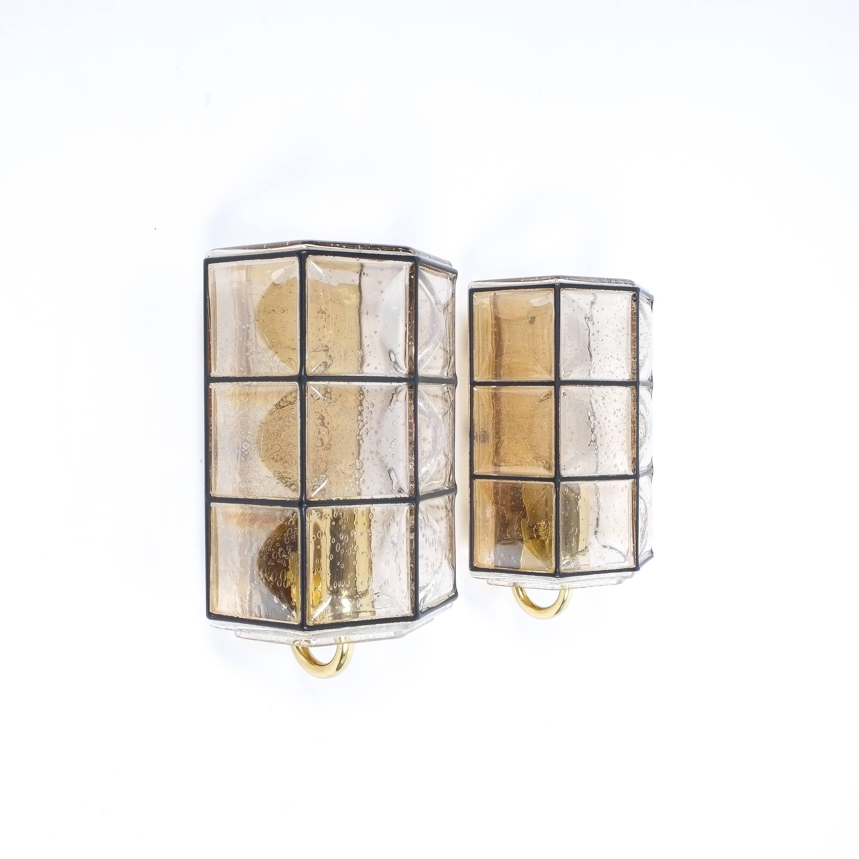 Beautiful pair of glass and brass wall fixtures by Limburg, Germany, 1960. They have been comprised of slightly amber colored glass with black grid accents and polished brass hardware. They are in excellent refurbished, rewired (110-220V) condition