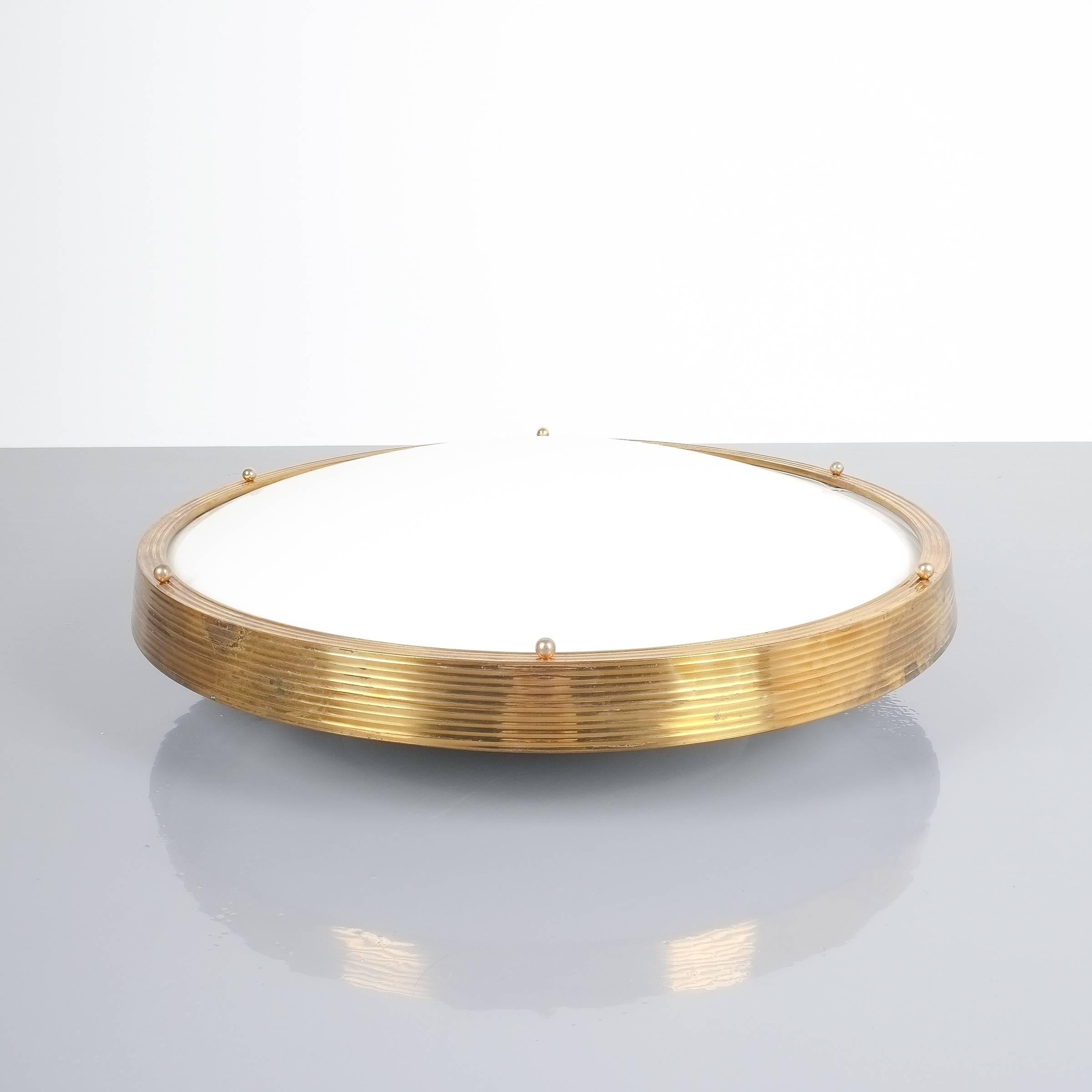Large Lucite brass cinema ceiling flush mount lamp, France, 1950. With 26.4 inches in diameter and 4x e27 bulbs this light is illuminating beautifully emitting a soft tone light. It is featuring a large Lucite dome shaped shade and a patinated brass