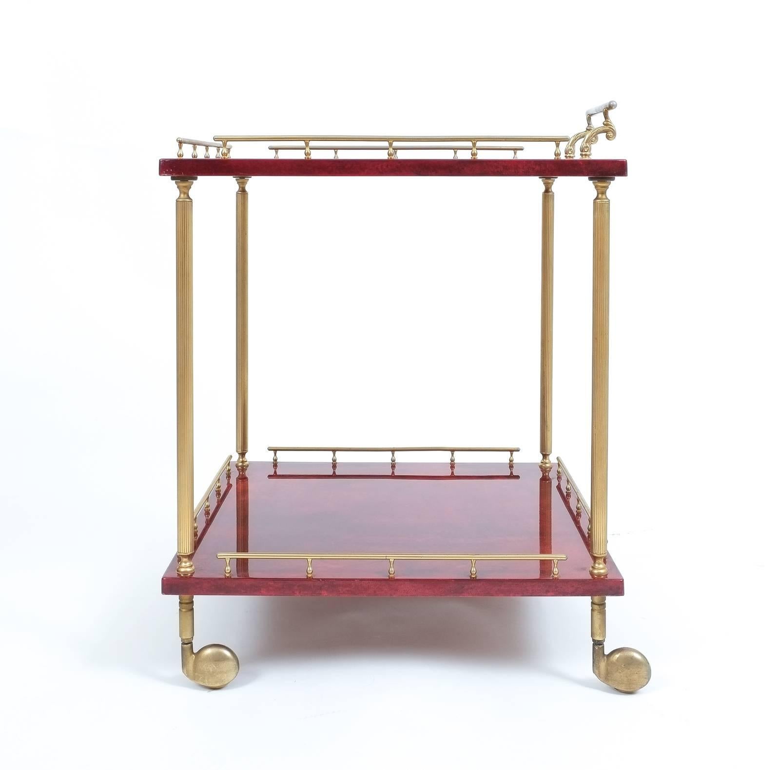 Elegant 22" x 22" liquor or bar cart by Aldo Tura Milan, Italy. It's composed of two square dyed lacquered goatskin trays (red) and polished brass hardware. The condition is excellent.