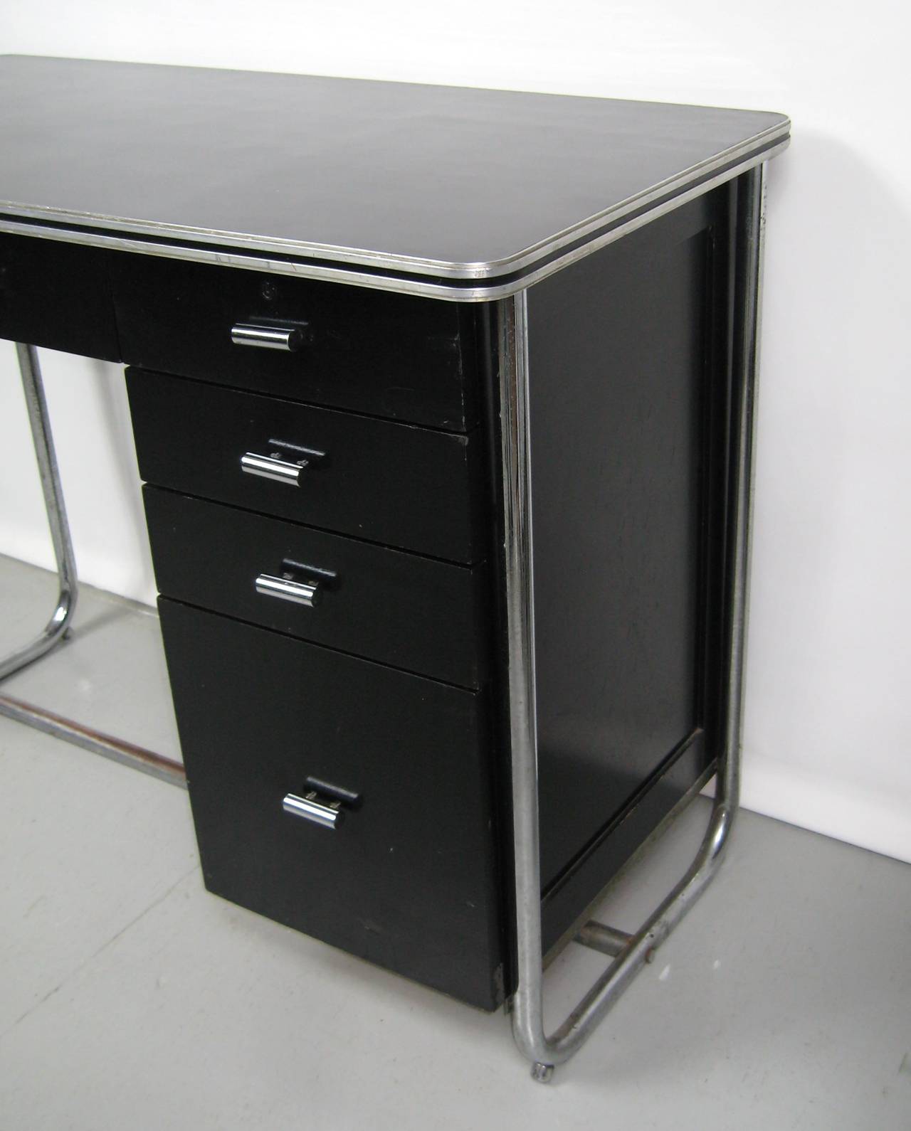 Late 1930s streamlined Art Deco office desk with laminate top. Very unique bent tubular chrome base with three pull-out enameled metal drawers. Original and intact chrome drawer pulls. Manufactured by the royal metal manufacturing co. It also has a