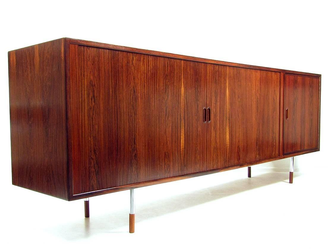 A beautiful 1960s sideboard in Rio Rosewood by Arne Vodder for Sibast.

It has perfectly-crafted tambour doors, steel legs and rosewood-tipped feet. 

The maple interior features adjustable shelving, baize-lined drawers and a dry bar on the