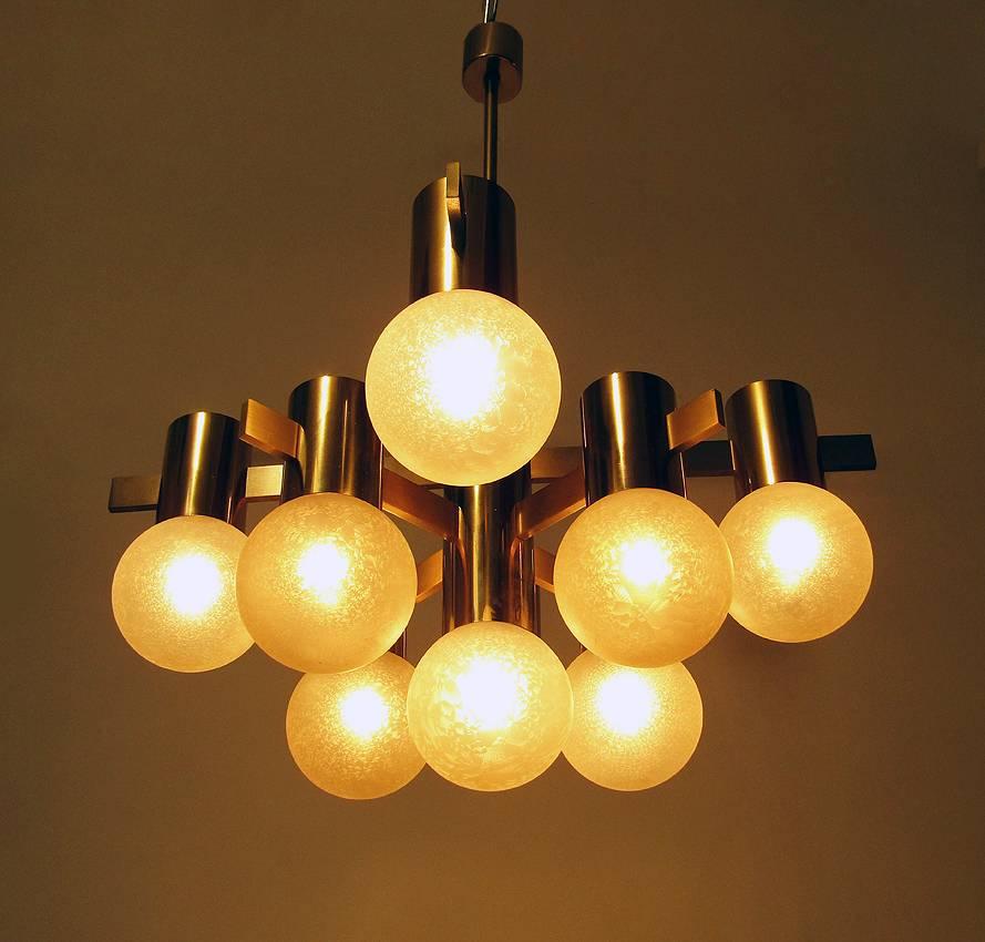 A geometric 1970s chandelier with amazing art glass shades by Swedish designer Hans Agne Jakobsson.

It has nine individual lights on three tiers supported by eight brushed brass arms.

The delicately textured glass orbs emit a soft, warm