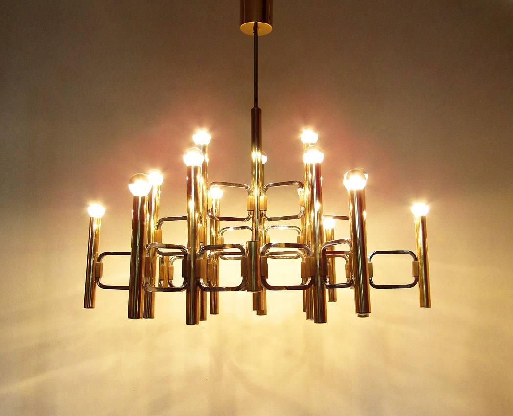 A large and impressive fifteen-light chandelier by Italian designer Gaetano Sciolari.

Dated circa 1975, it is comprised of brass and chromed steel with chromed end caps and original brass ceiling rose.

The fifteen light sources emit a diffused
