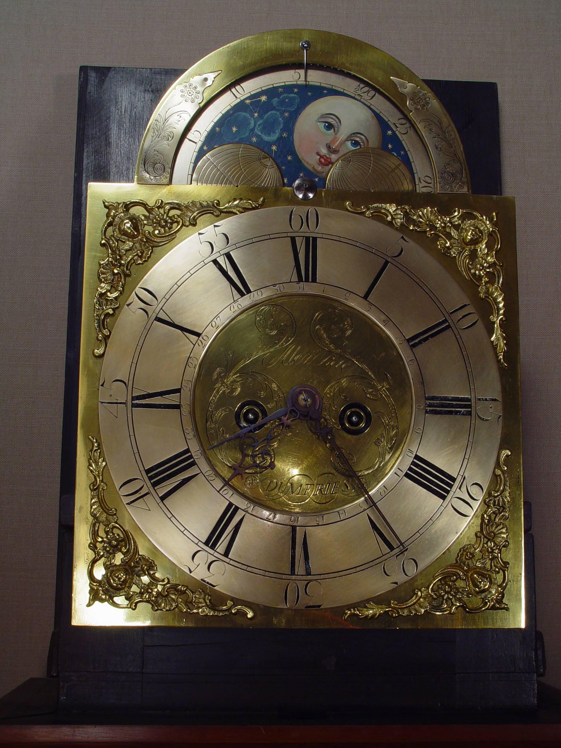 An English mahogany longcase clock with moon phase and date Alex Rae Dumfries, circa 1770 arched brass dial with silvered chapter ring, center with foliate scrolls signed Alex Rae Dumfries, foliate pierced blued hands and date pointer, foliate mask