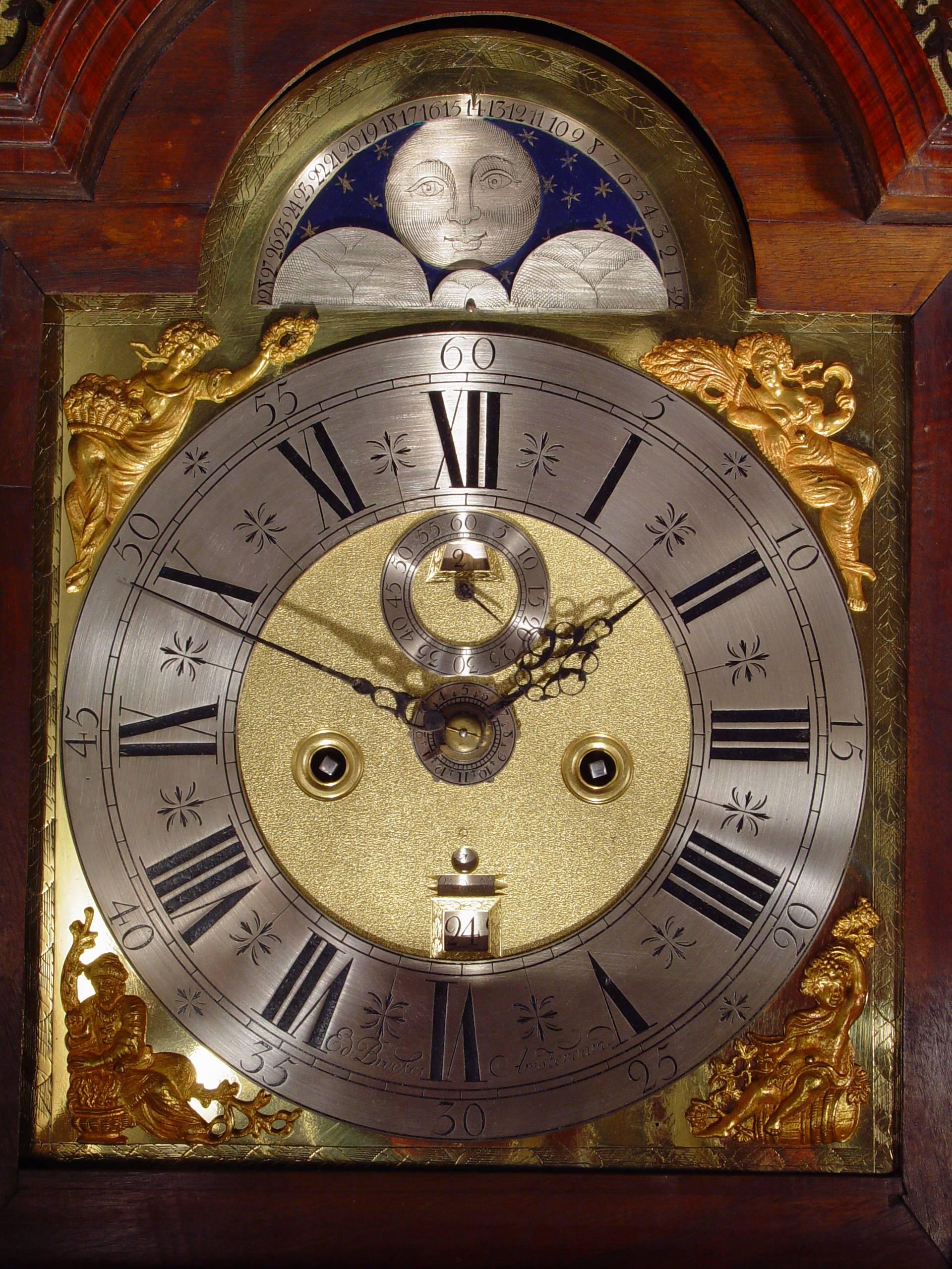 A Dutch burr walnut striking alarm longcase clock with calendar Ed Brookes, circa 1725. 

Brass dial with early arch and engraved wheatear border, silvered engraved chapter ring signed Ed Brookes Amsterdam, pierced blued hands and slivered alarm