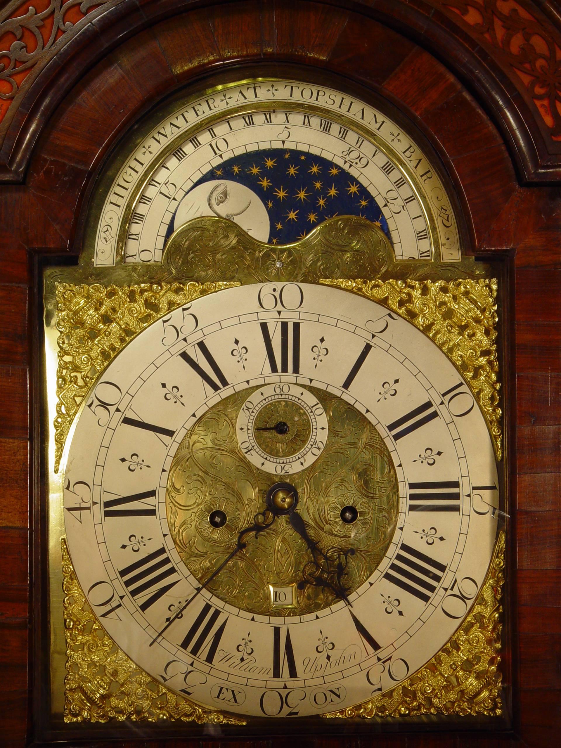A good and attractive English walnut longcase clock with moon phase by William Upjohn, circa 1730.
arched brass dial with silvered engraved chapter ring signed William Upjohn Exon, blued hands and finely pierced gilt mask spandrels, foliate