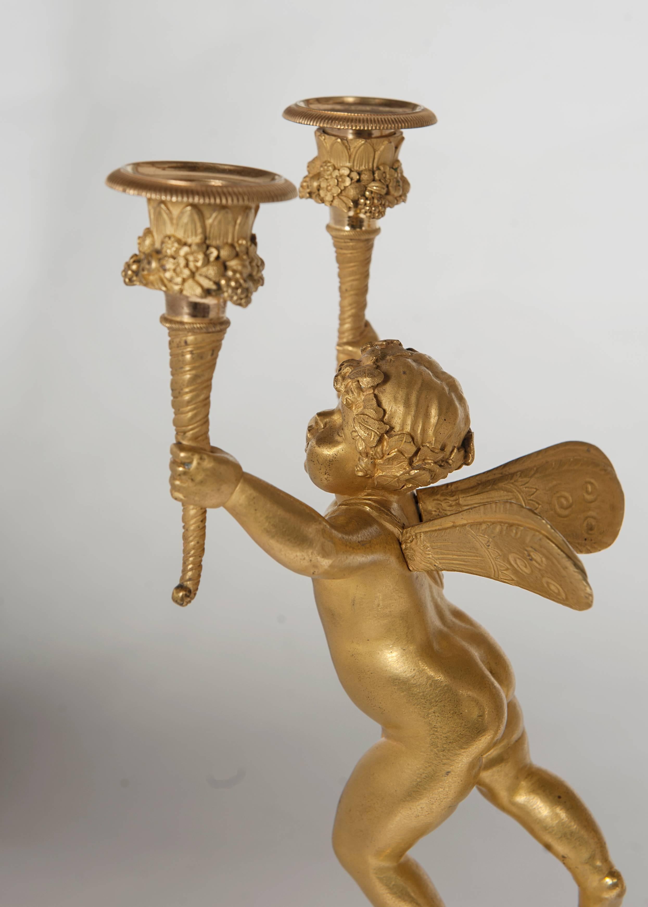 A pair of two-armed Empire ormolu candlestick with cupids on a circular base. The detailed castings of the bronzes are very nice, circa 1820.