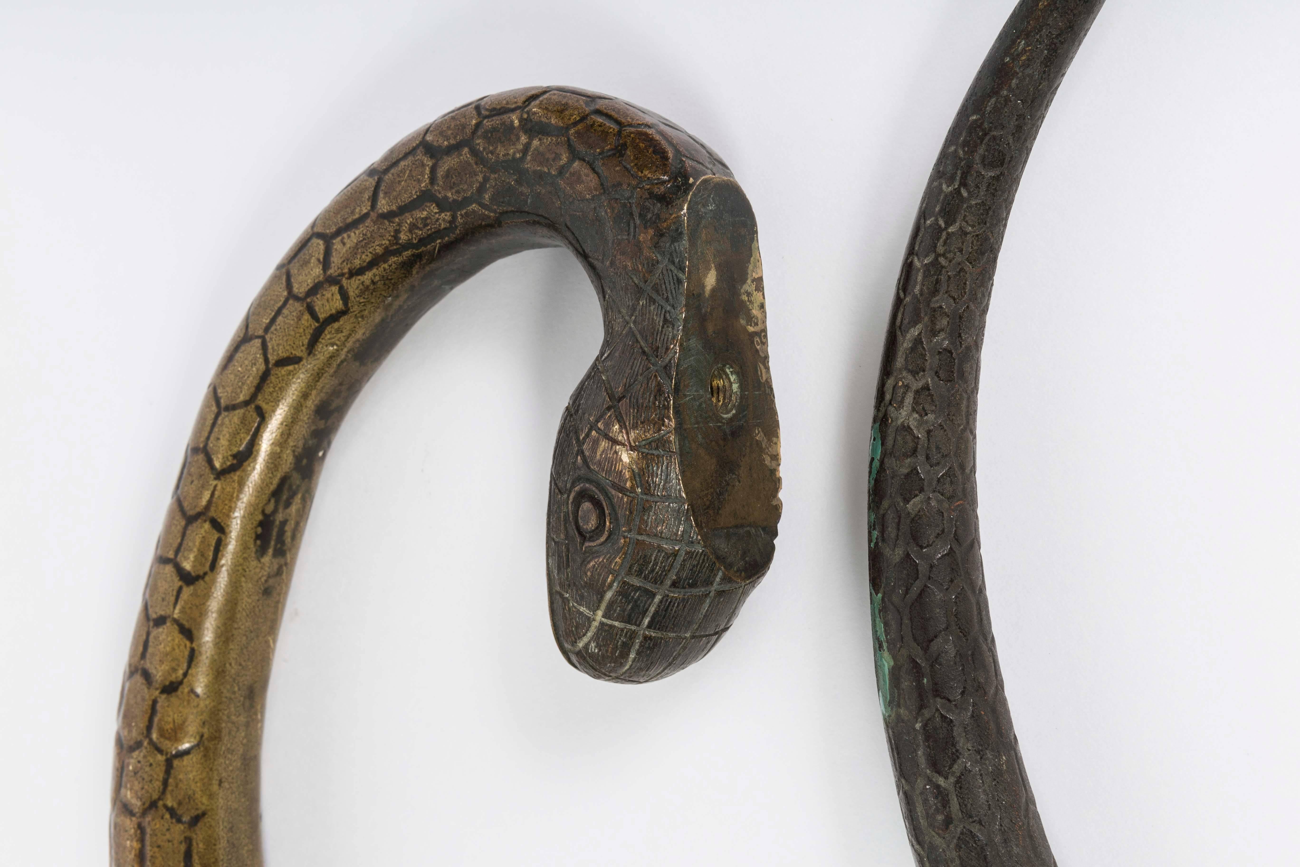 This is a very unusual pair of 19th Century bronze door handles fashioned in a curving snake design. This pair of bronze snake handles are large in size and very heavy which makes them impressive.  They have a very smooth finish with intricate