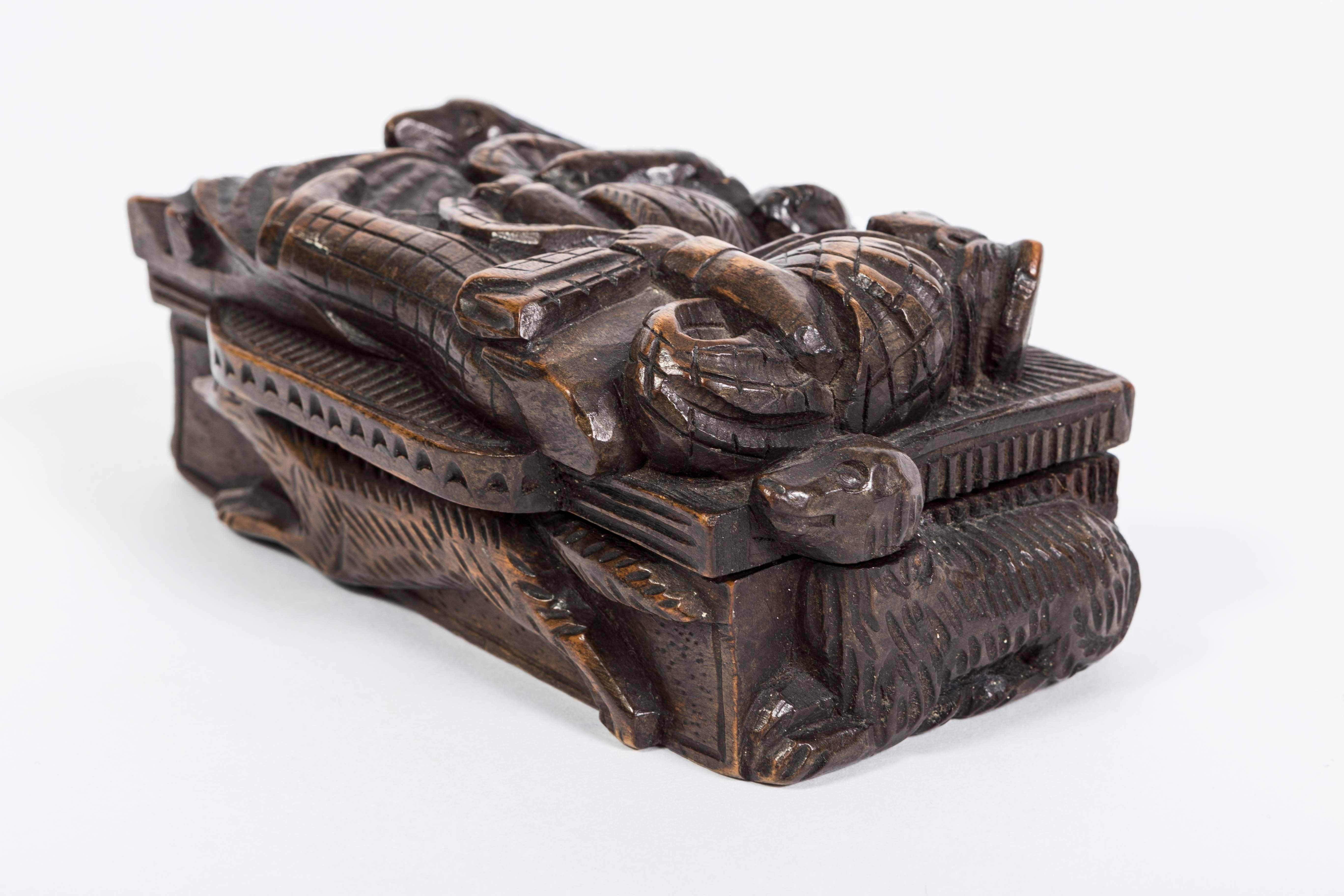 This 19th Century wooden hand-carved box, carved all the way around with fo, dogs and men has a  hinged top. The carving consist of a fox on the front, dogs on the side and two men on the top. Beautifully carved with fine detail.