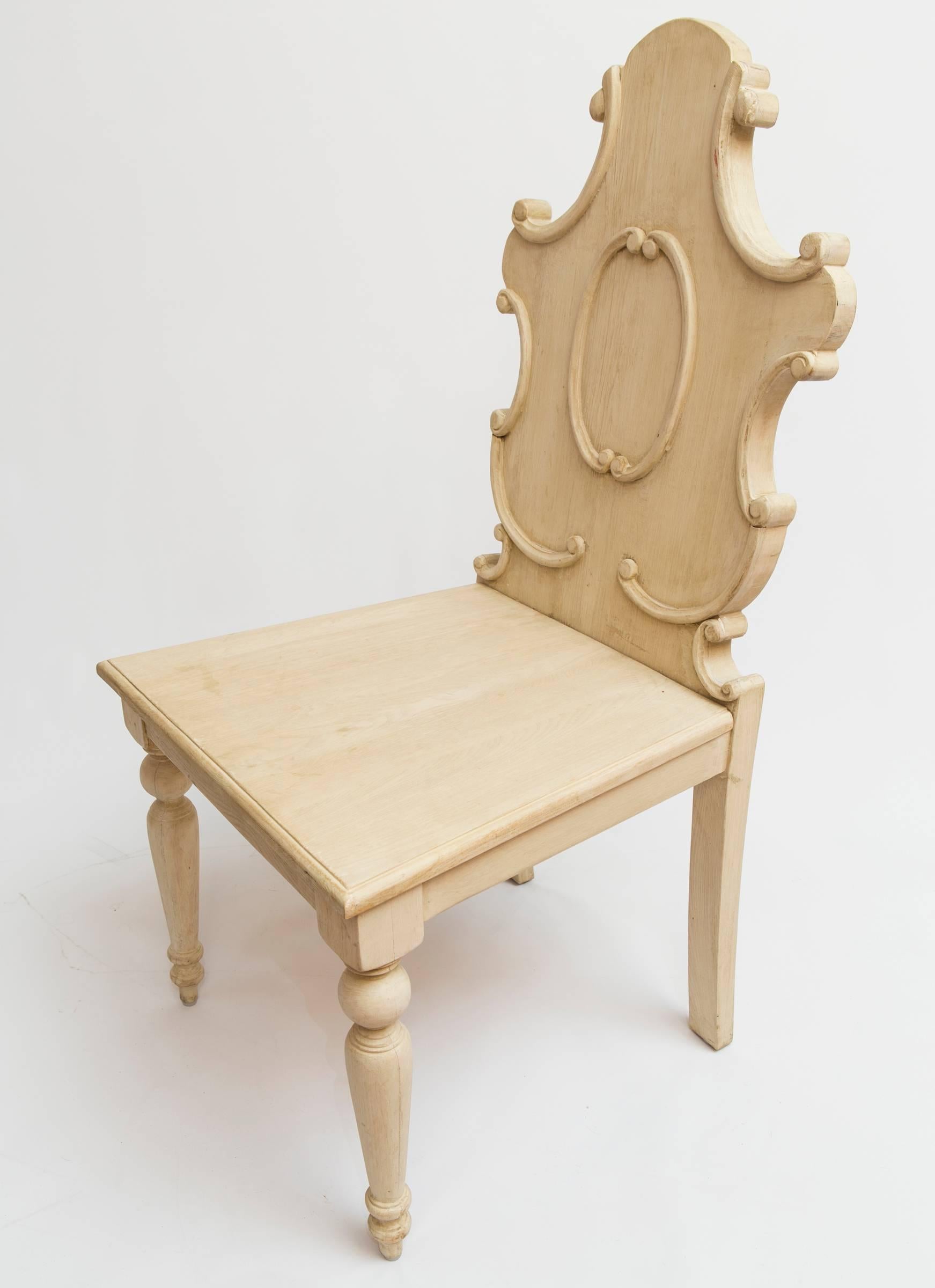 Pair of sculptural wooden side or hall chairs in painted wood.  The chairs have a shaped back with scroll details and a wood seat.  
