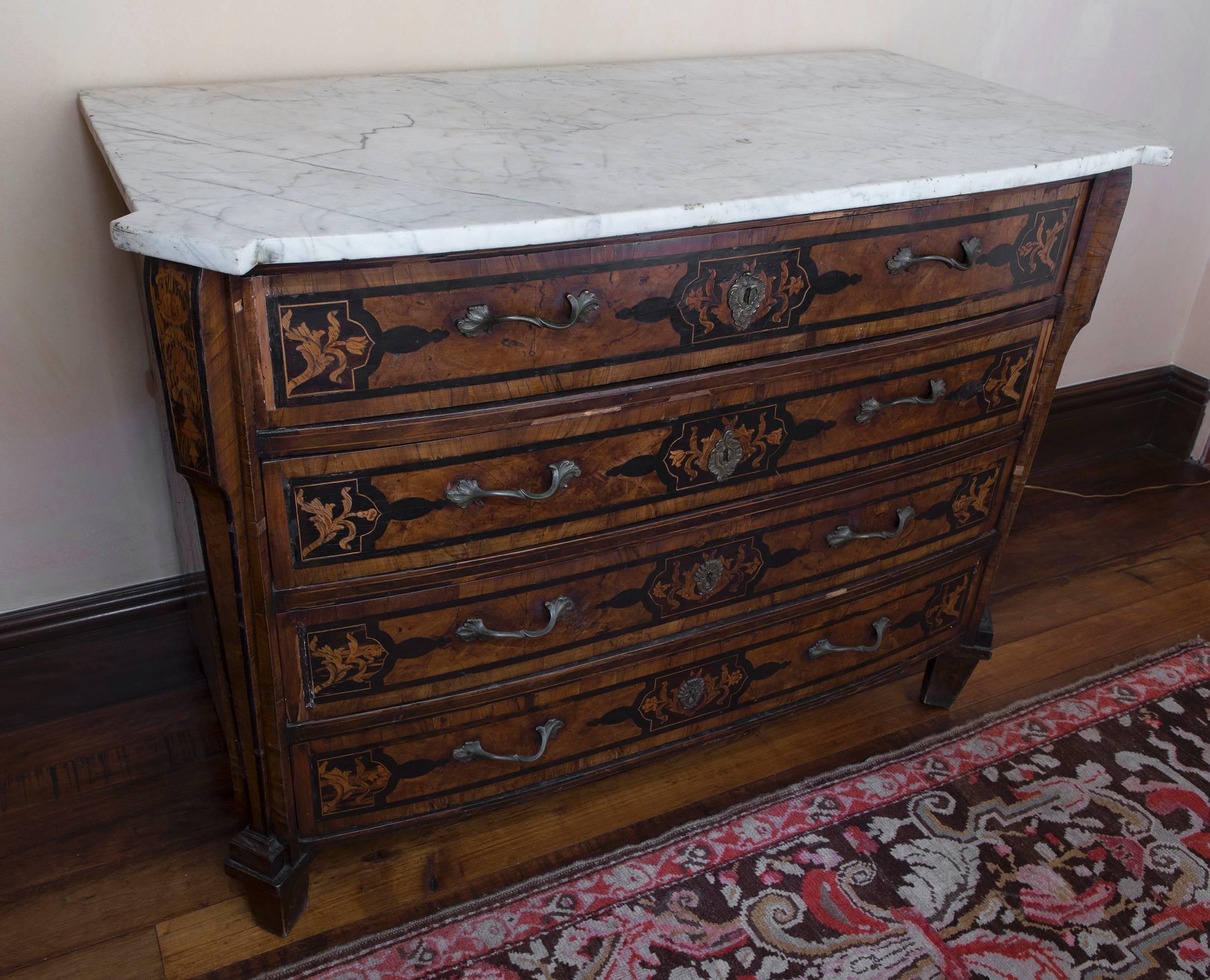 18th century Italian walnut veneered commode of serpentine and bombe shape, floral marquetry with white marble top.