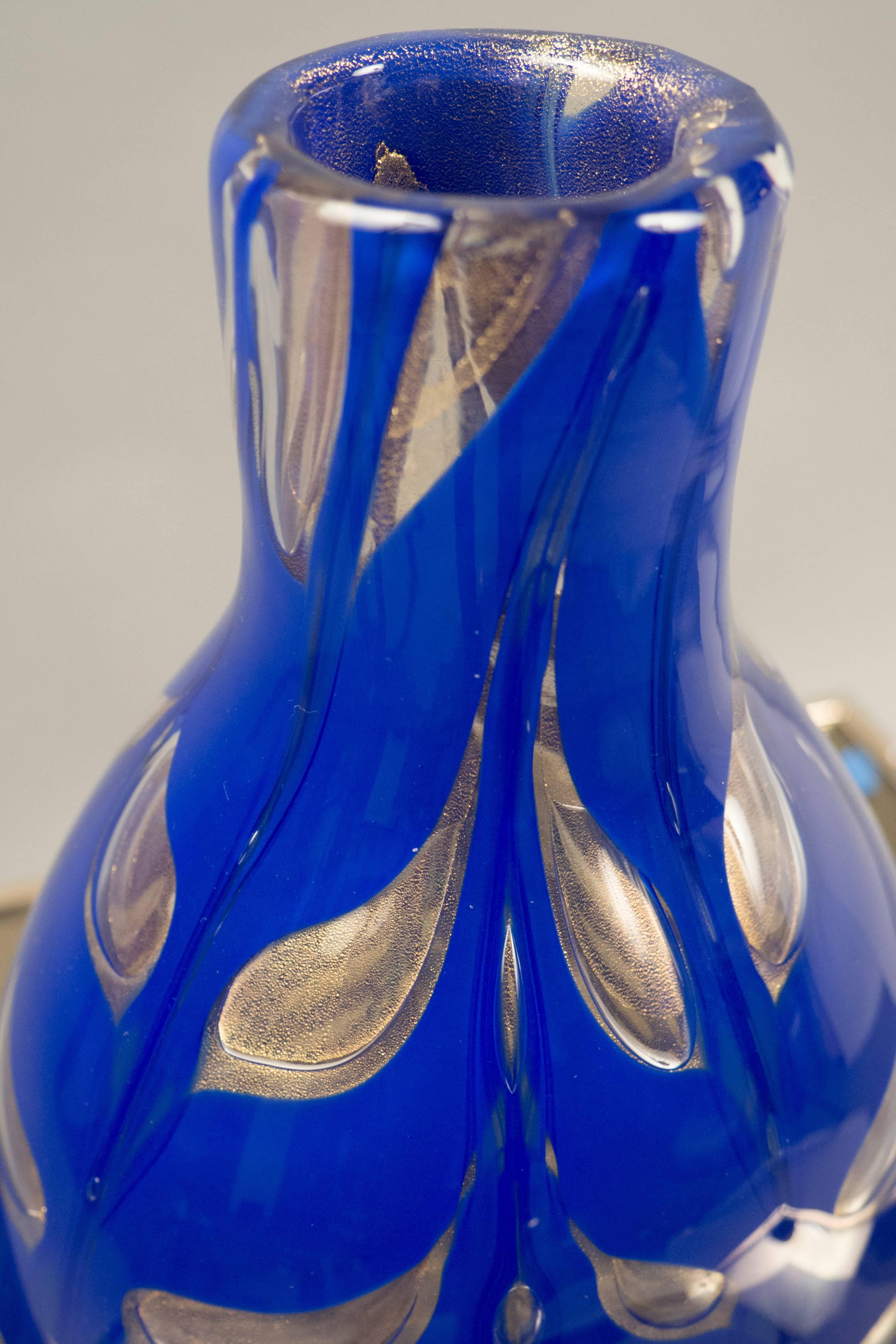 Vase en verre bleu royal en forme de flasque avec des décorations claires en forme de feuilles et des inclusions de poussière d'or. Signé en bas.
   