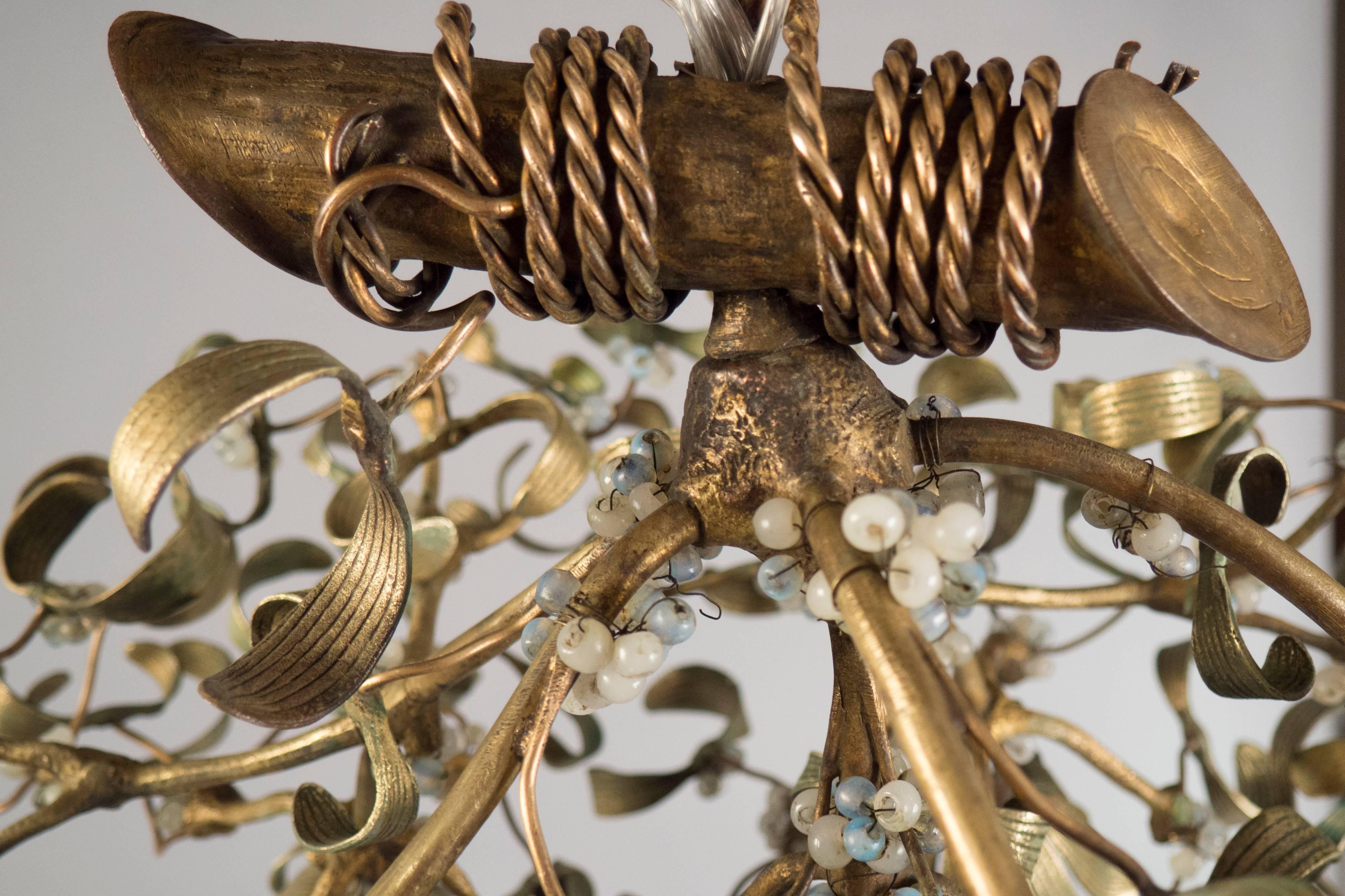 Green-brown patinated bronze chandelier in the shape of a mistletoe, featuring a roped off branch and numerous opaline glass pearls throughout.