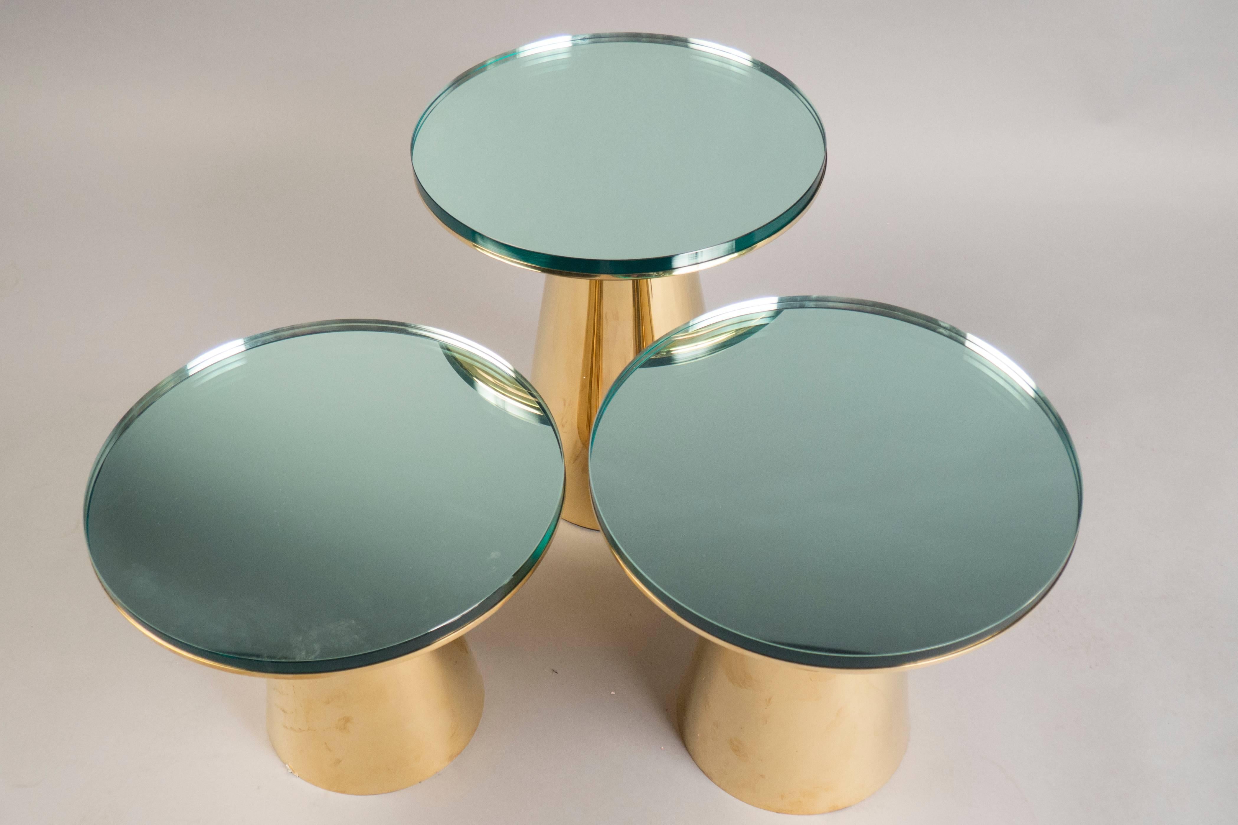 Each table composed of a conical polished brass base, supporting a circular thick mirrored top. 

Table 1: Height: 19.25