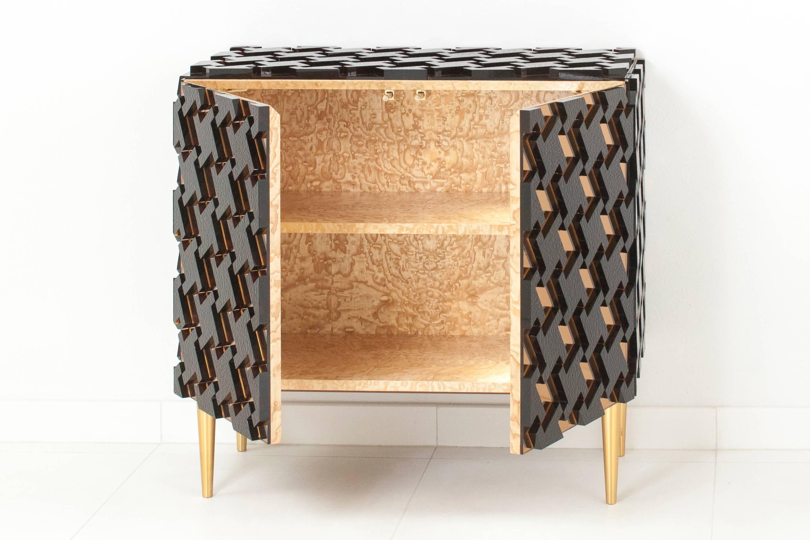 Unique piece, featuring a houndstooth pattern made of apricot mirrored glass overlaid with rippled amber glass sections, raised on brass legs, which feature a leveling system. The blonde wood interior holds one shelf. Model 