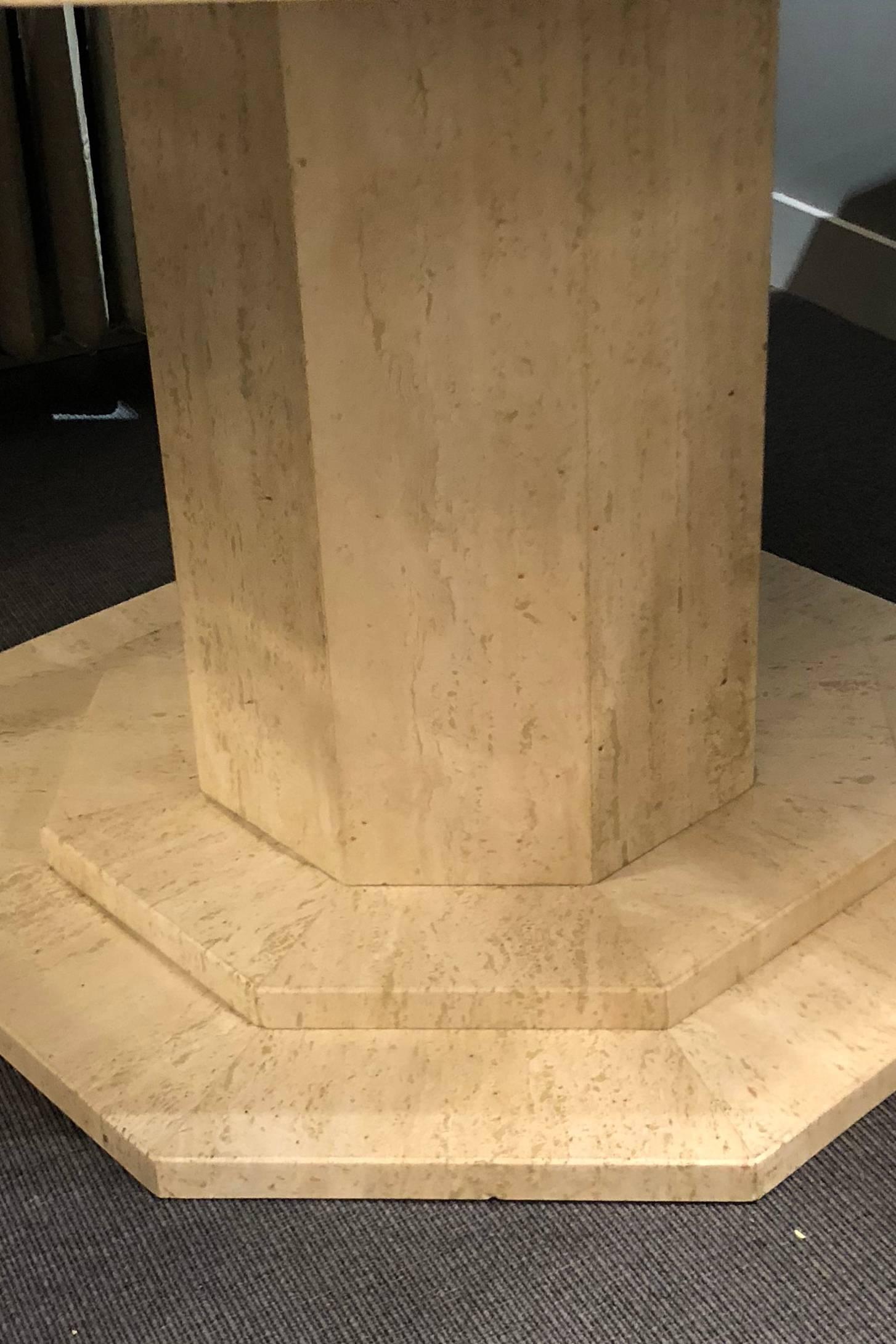 Travertine center table consisting of an octagonal top with brass trim, raised on an octagonal base and column of the same material.
 