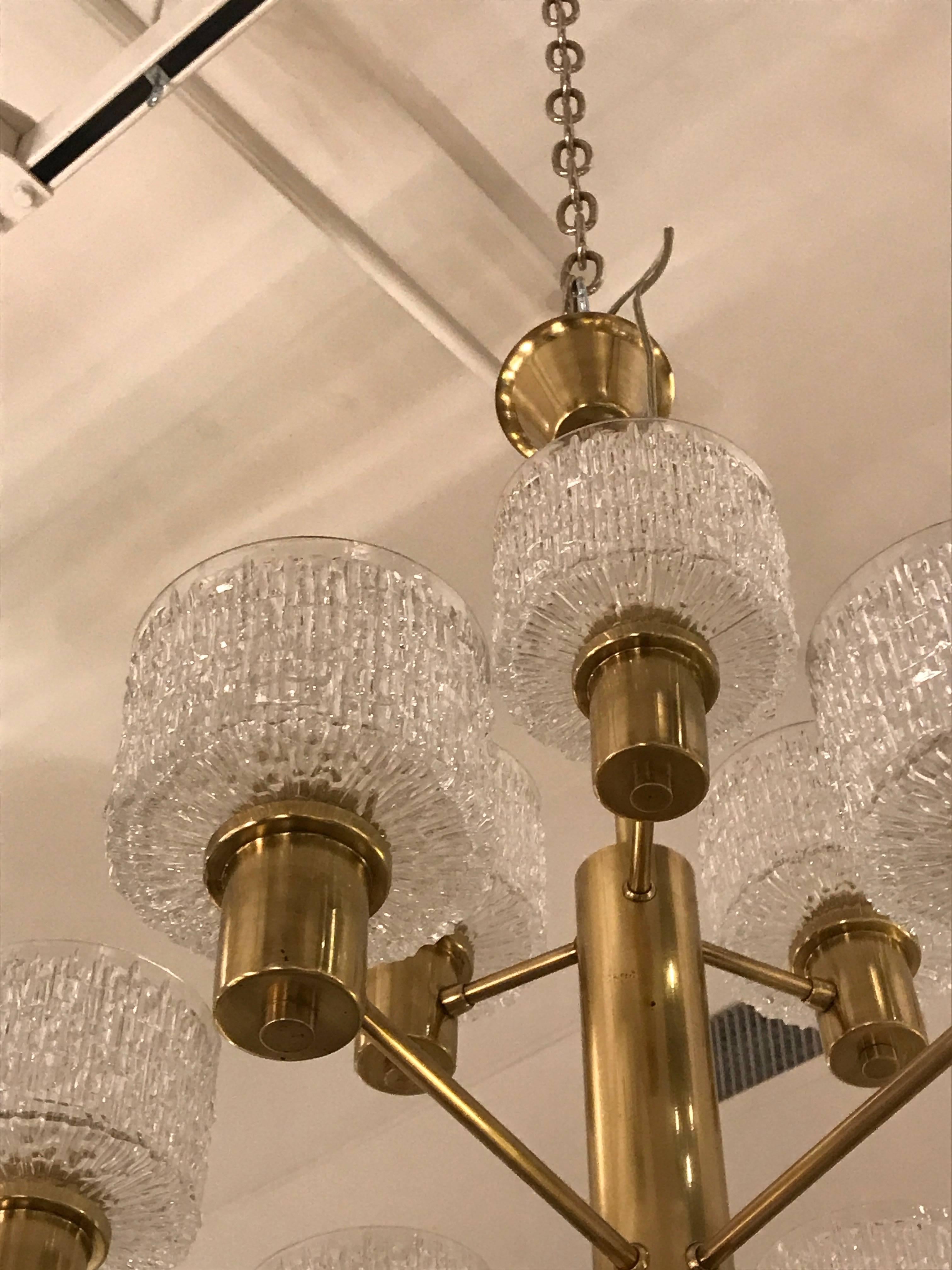 Brass nine-arm chandelier, arranged in two tiers, and fitted with textured mold-cast shade of clear glass.

  
