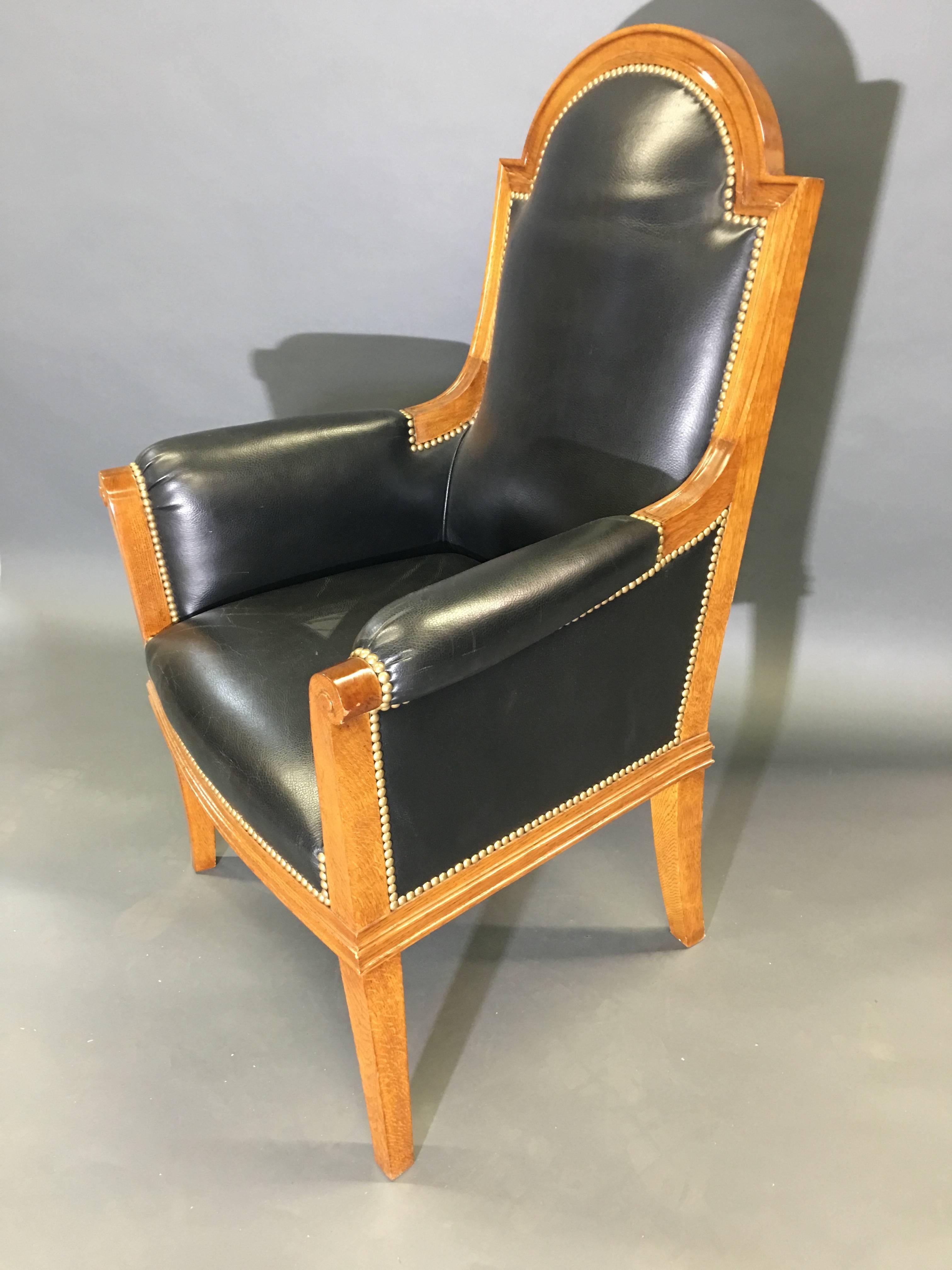 Solid oak upholstered in black leather, with an arched crest rail, upholstered rests and square supports headed with a scroll, atop four tapered and square legs.

OUR REFERENCE N5255