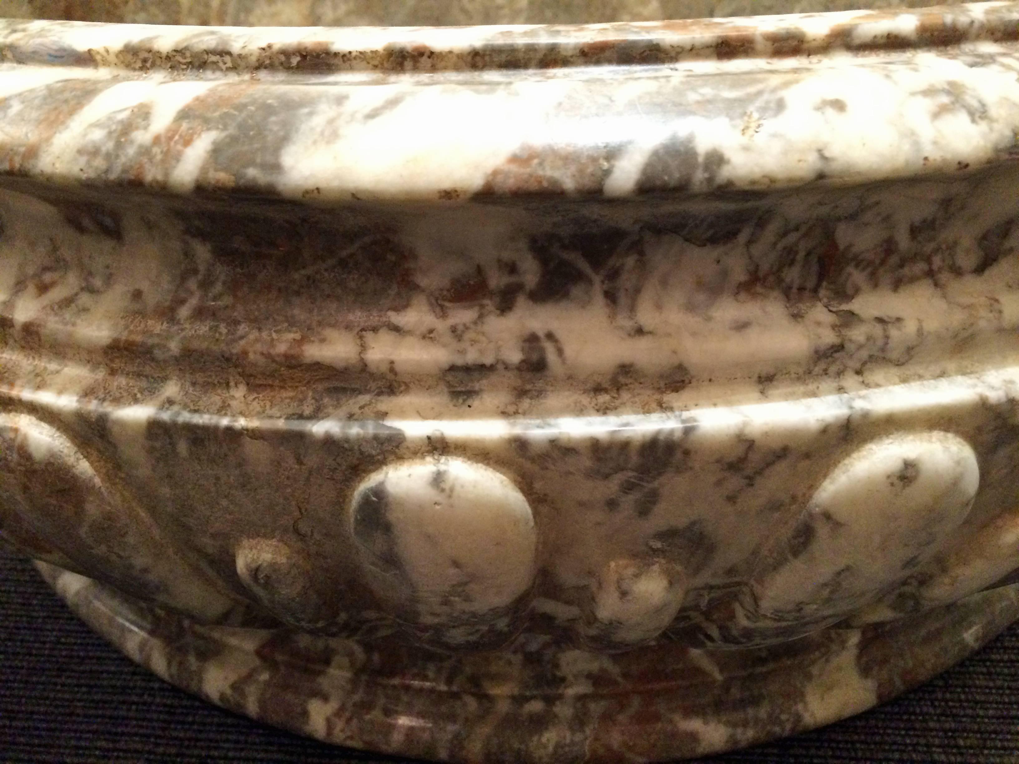 Oval marble bowl with carved drop-shaped decorations on the exterior.



   