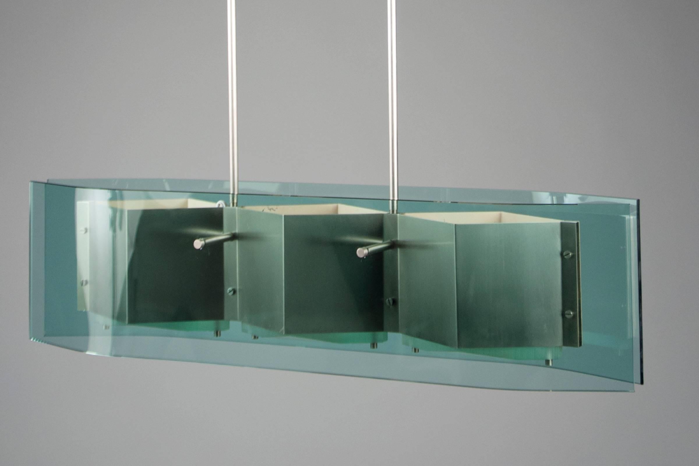 Two metal stems suspending two blue-green curved glass panels encompassing a three-part nickel structure.
   


