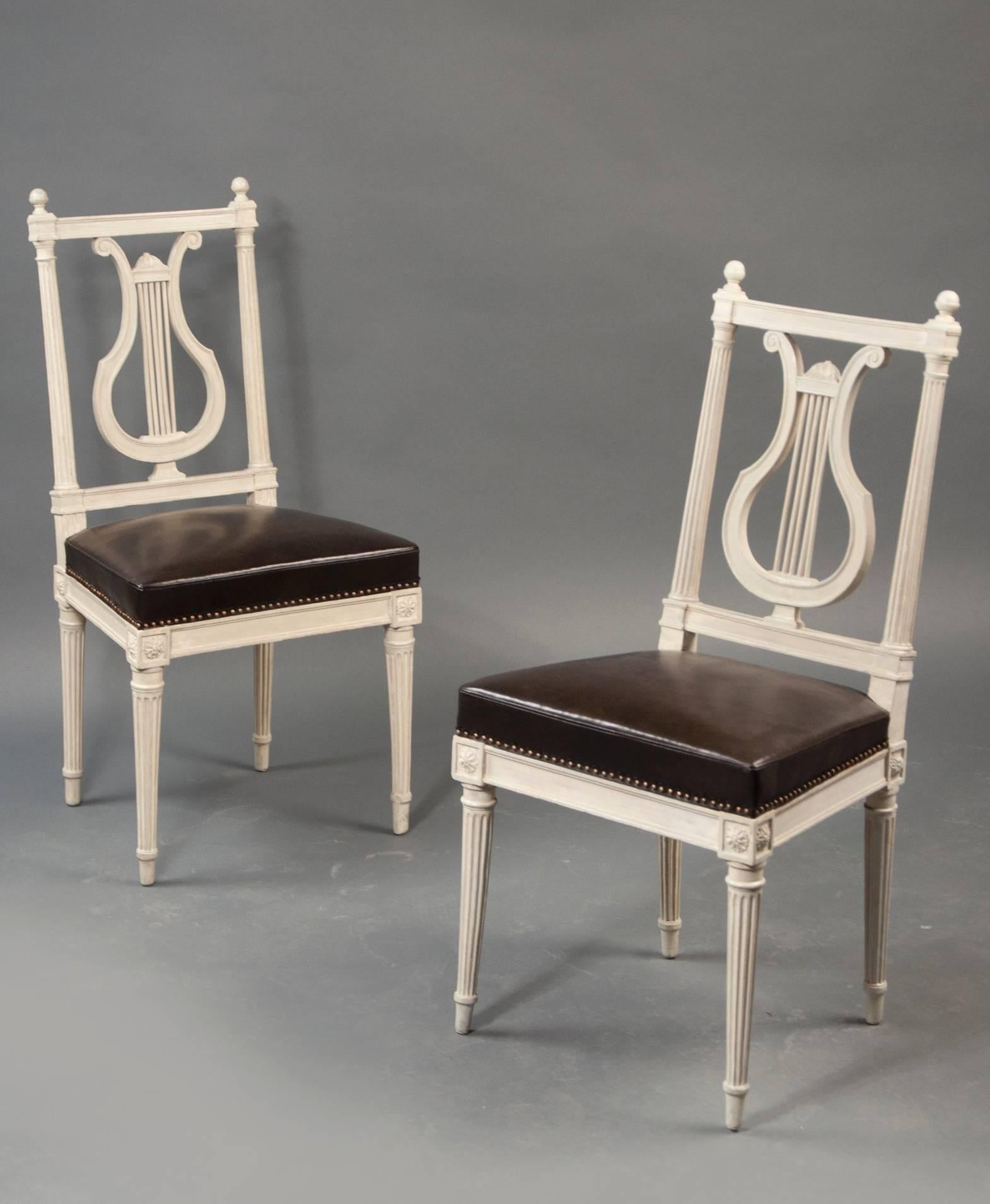 Carved and painted wood with an open lyre-form slat back; over an upholstered, trapezoidal seat; raised on tapered and fluted legs headed with rosettes.
 