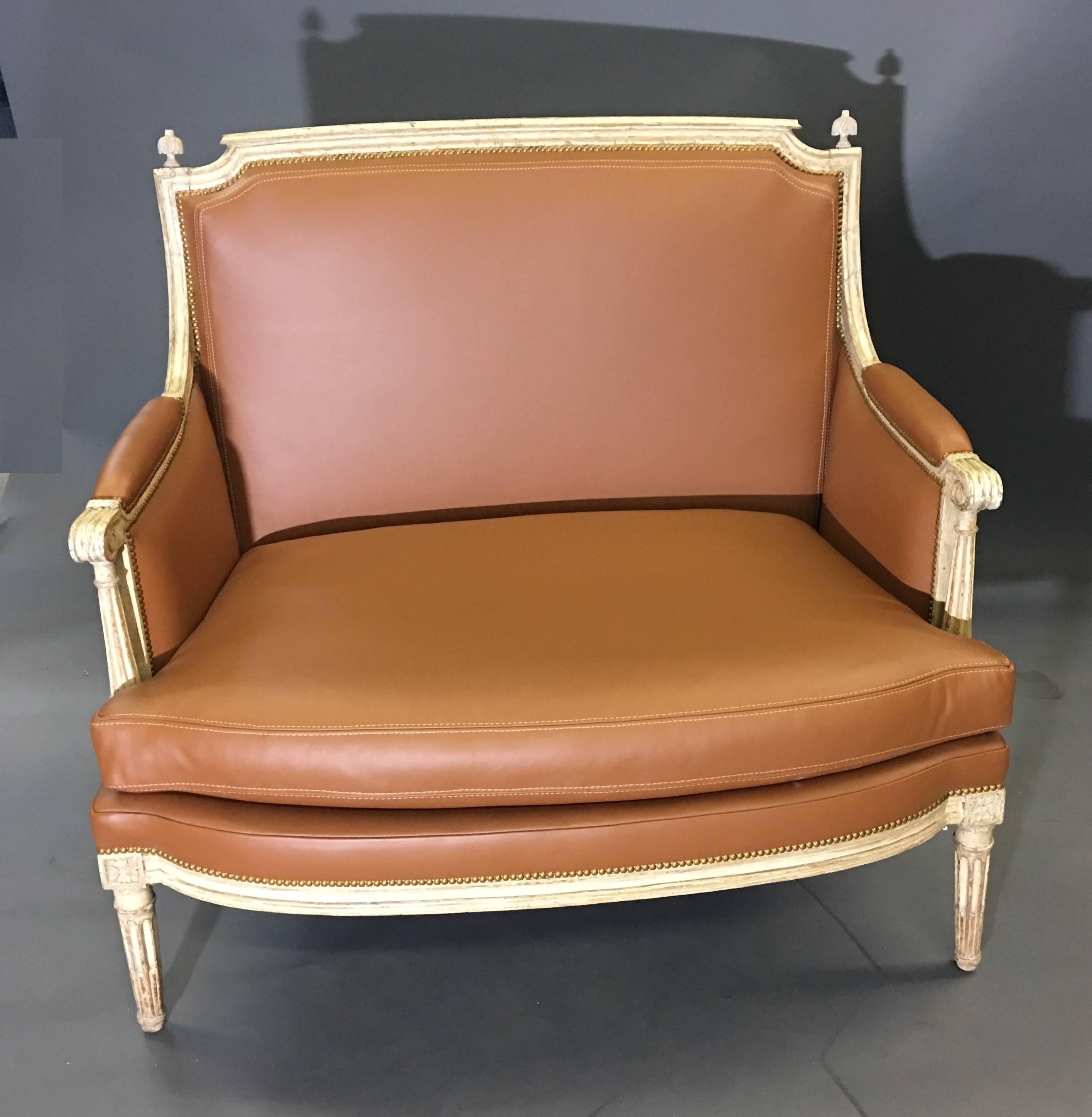 Carved and off-white lacquered wood, upholstered with a cushion seat; the rectangular back connects to padded armrests, ending in scrolls, above curved and fluted supports, raised on tapered and fluted legs headed with rosettes. Partial stamp