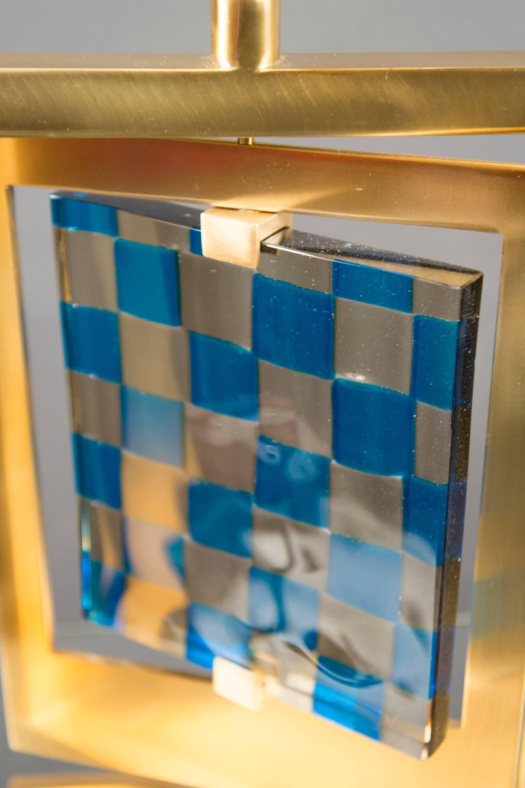 Model “Giroscopio”. Each lamp with a rectangular brass frame mounted to a central stem, which swivels around a blue and gray checkered vintage glass panel, produced by Venini.
 
(Lamp shade not included)