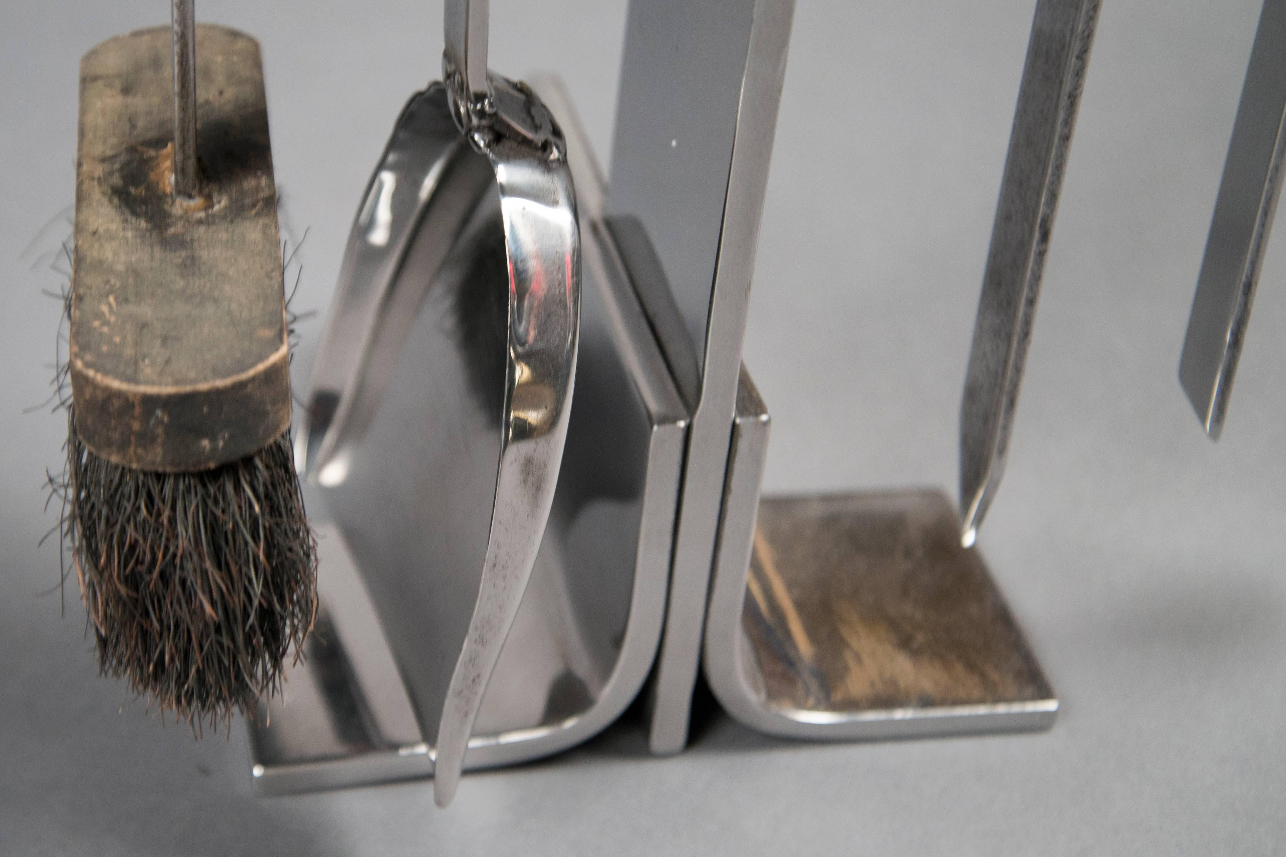 Chrome-plated fire tools, consisting of a shovel, tongs, brush and poker arranged on a stand.
           