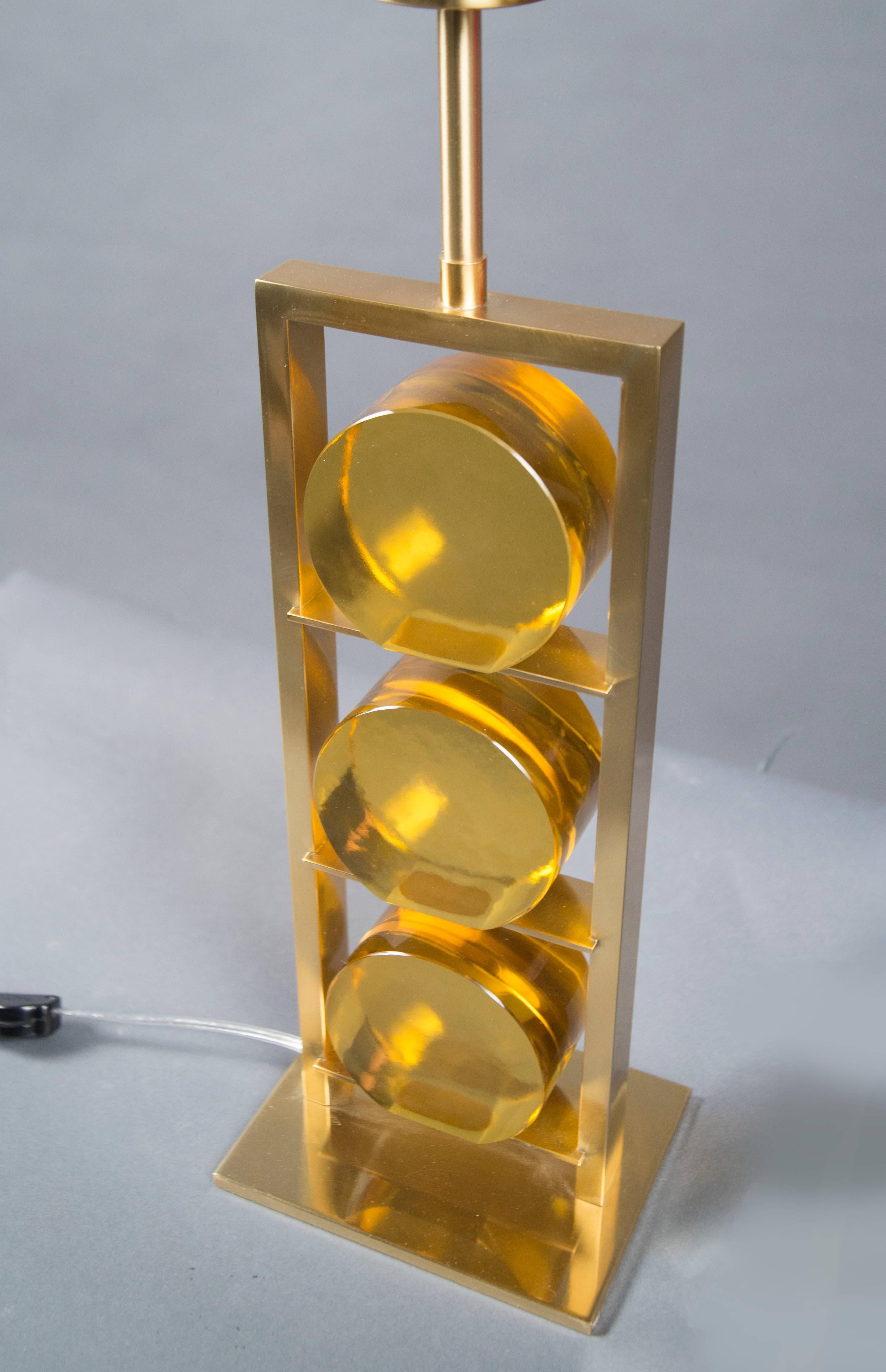 Each lamp composed of a rectangular brass frame holding three polished amber glass disks, raised on a flat brass base. Model “Casette”.



  