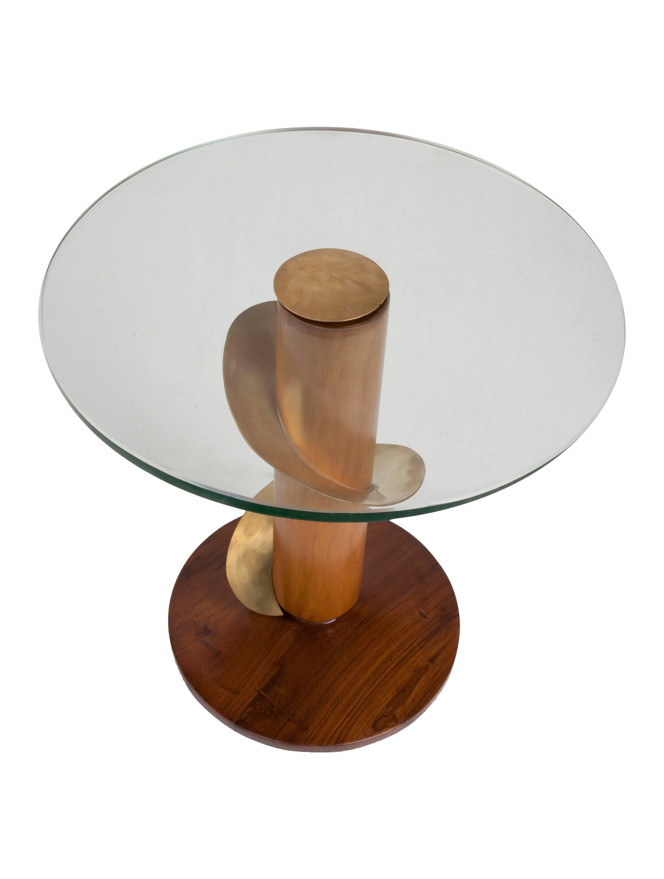 Teak and brass side tables with a swirl of brass around the stem and glass tops. Glass piece can be removed by taking off the brass center piece. Diameter of the base is 12 inches. Mid-Century Modern.

Mid-Century Modern pieces located on
