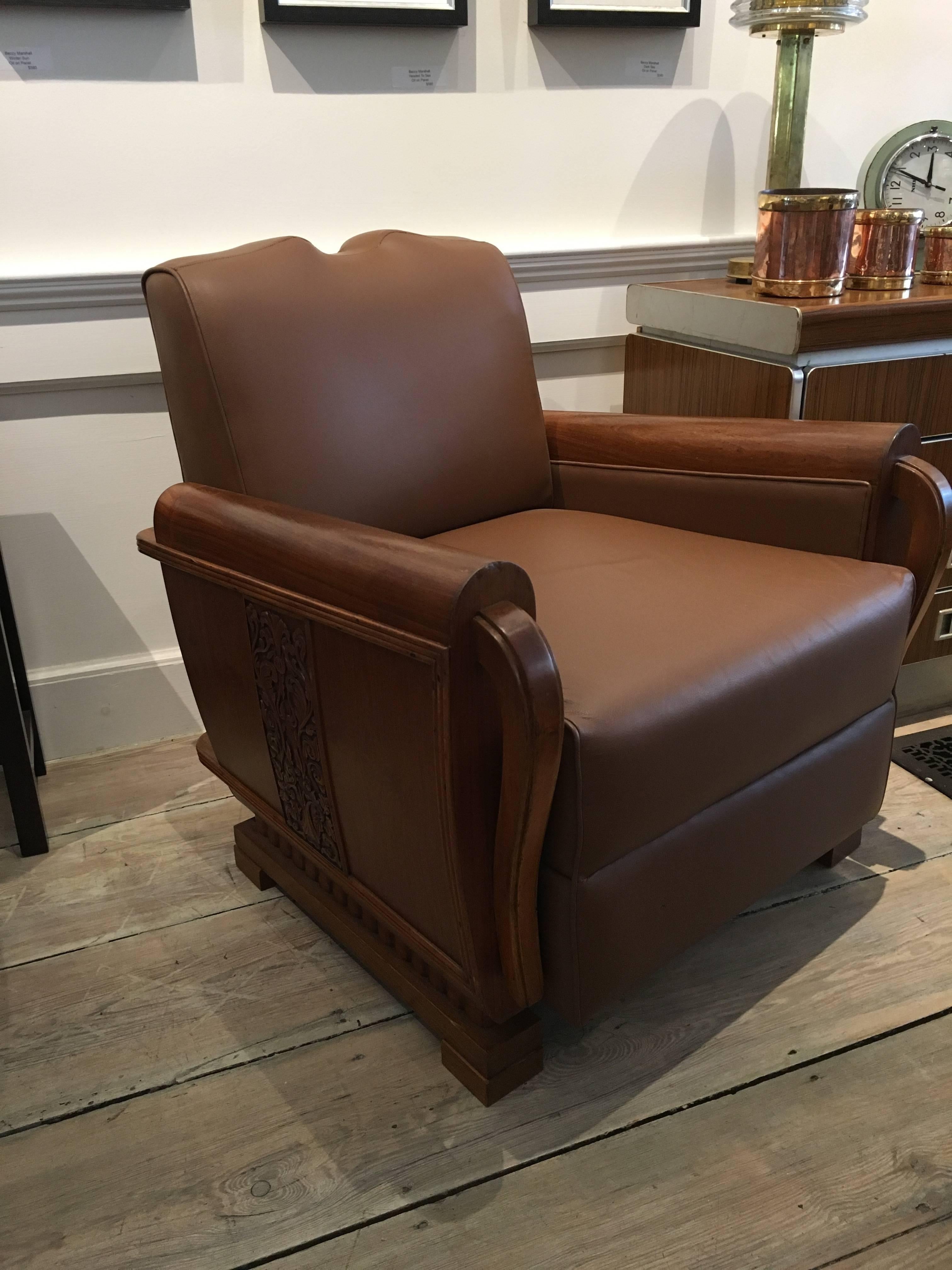 Pair of art deco period teak and leather club or lounge chairs with beautifully carved detail along the sides with a mustache back. These are substantial and incredibly well made. The leather upholstery is not original but in good condition having